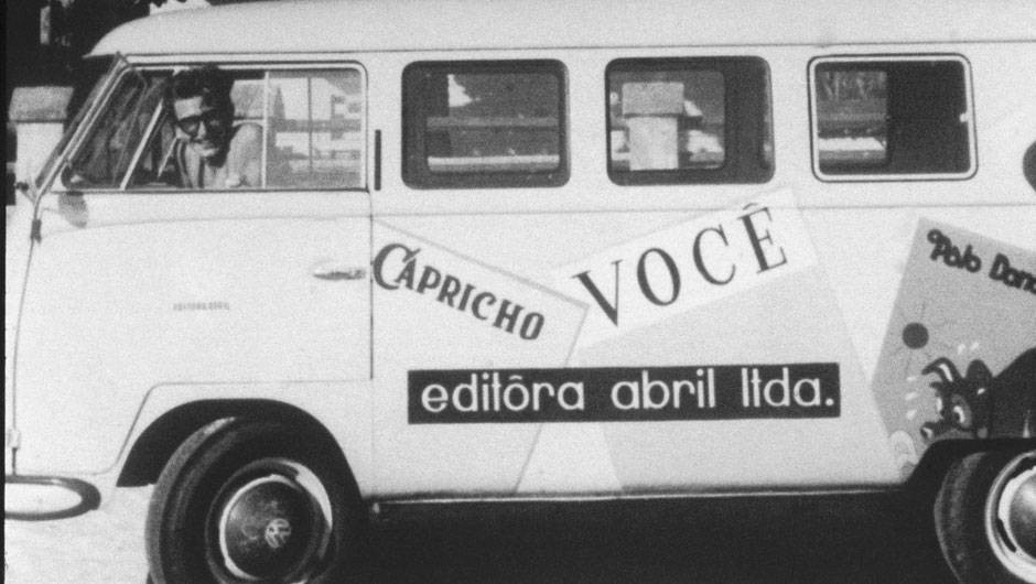 Roberto Civita dirigindo uma Kombi com logotipos de revistas da Editora Abril, no final da d&eacute;cada de 50.