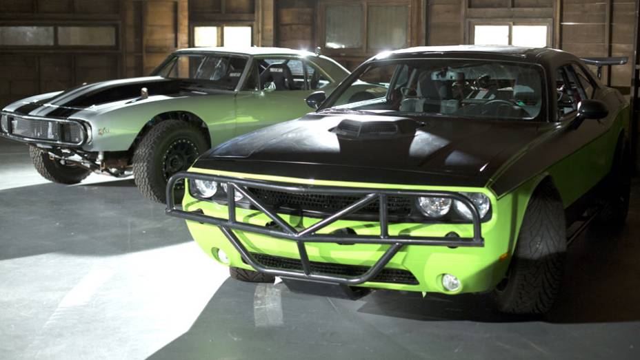 Além do Cuda, Letty também pilota um Dodge Challenger verde bastante modificado; ao fundo, o Chevrolet Camaro de Roman Pearce (Tyrese Gibson) | <a href="https://beta-develop.quatrorodas.abril.com.br/galerias/especiais/gatas-velozes-furiosos-852096.shtml" target="_blank" rel="migration">7</a>