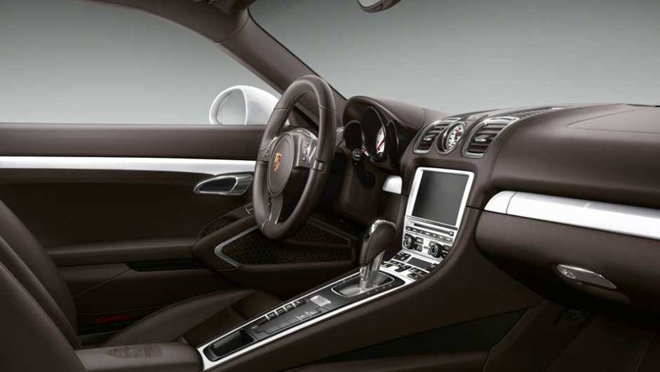 O interior tem revestimento em couro marrom com apliques brancos pela cabine | <a href="https://beta-develop.quatrorodas.abril.com.br/noticias/fabricantes/porsche-cayman-s-ganha-personalizacao-fabrica-894381.shtml" rel="migration">Leia mais</a>