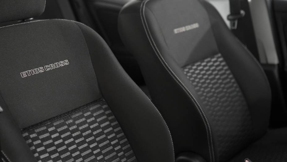 O revestimento Sport Comfort nos bancos ganhou costura branca e apresenta o nome do ve&iacute;culo gravado em alto relevo no encosto dos assentos dianteiros | <a href="https://beta-develop.quatrorodas.abril.com.br/carros/lancamentos/toyota-etios-cross-759424.shtml" rel="migration"></a>