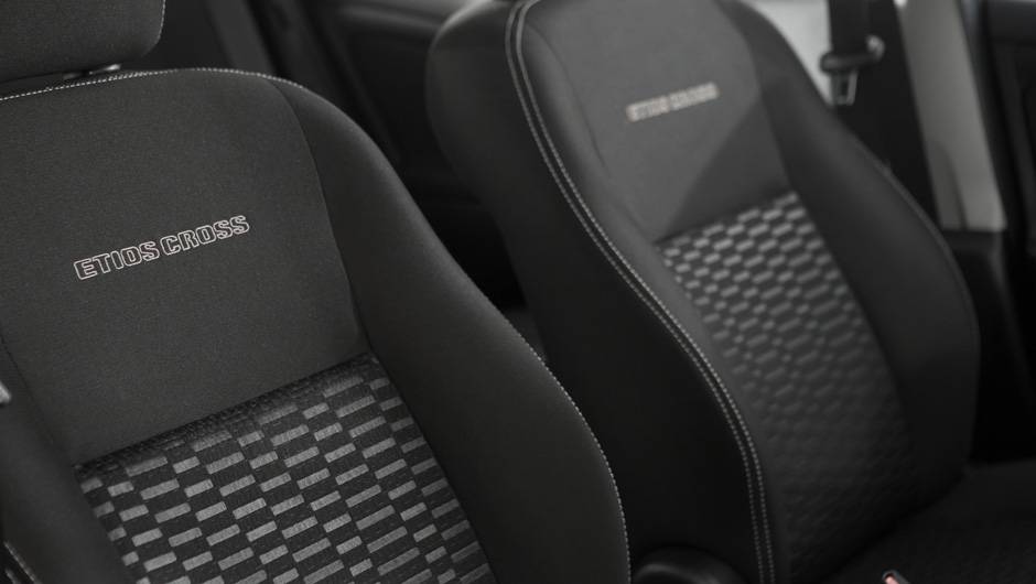 O revestimento Sport Comfort nos bancos ganhou costura branca e apresenta o nome do ve&iacute;culo gravado em alto relevo no encosto dos assentos dianteiros | <a href="https://beta-develop.quatrorodas.abril.com.br/carros/lancamentos/toyota-etios-cross-759424.shtml" rel="migration"></a>