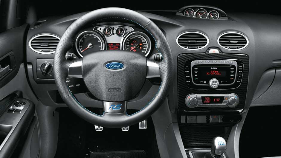 A sigla RS, no volante, vem de Rallye Sport. <a href="https://beta-develop.quatrorodas.abril.com.br/carros/impressoes/ford-focus-rs-636939.shtml" rel="migration">Leia mais</a>