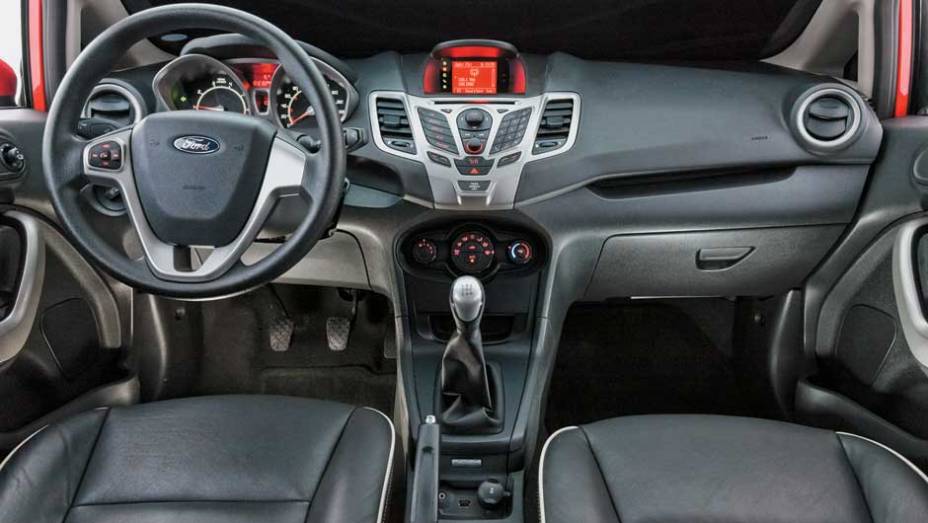 Formato dos botões centrais não favorece a ergonomia | <a href="https://beta-develop.quatrorodas.abril.com.br/carros/comparativos/ford-new-fiesta-x-chevrolet-sonic-699387.shtml" rel="migration">Leia mais</a>