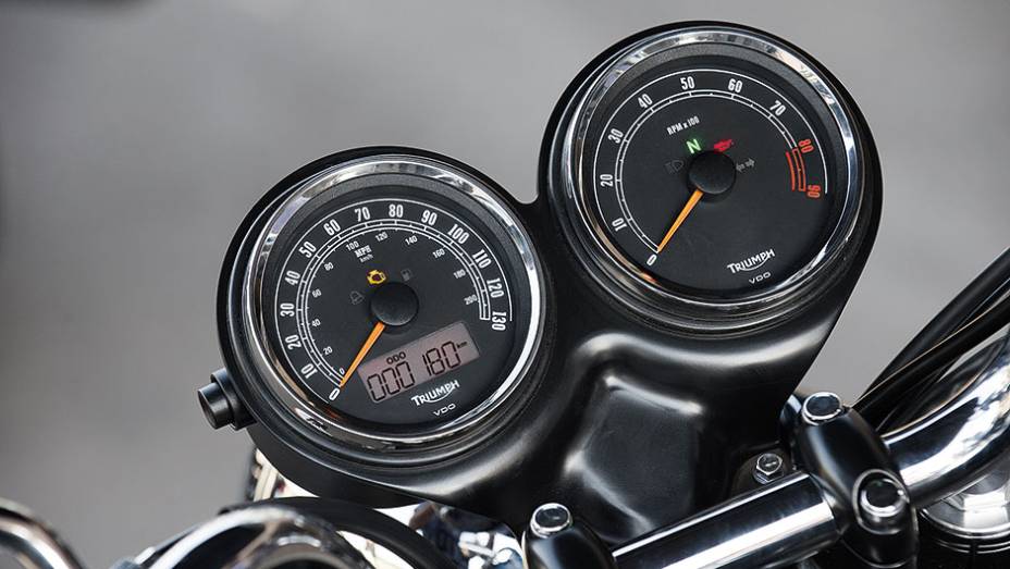 Painel com 2 visores redondos e pequeno LCD | <a href="https://beta-develop.quatrorodas.abril.com.br/moto/testes/triumph-bonneville-t100-741213.shtml" rel="migration">Leia mais</a>