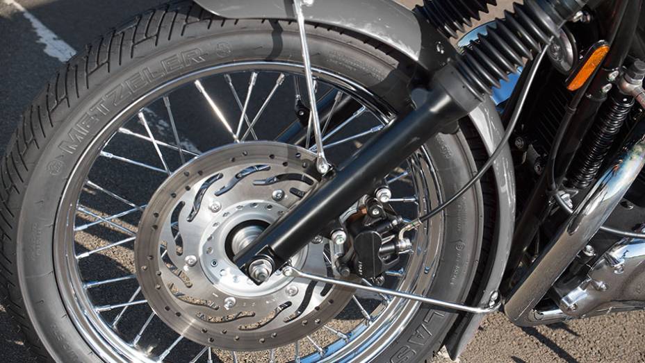 Bons pneus, um disco frontal e rodas raiadas na versão T100 | <a href="https://beta-develop.quatrorodas.abril.com.br/moto/testes/triumph-bonneville-t100-741213.shtml" rel="migration">Leia mais</a>