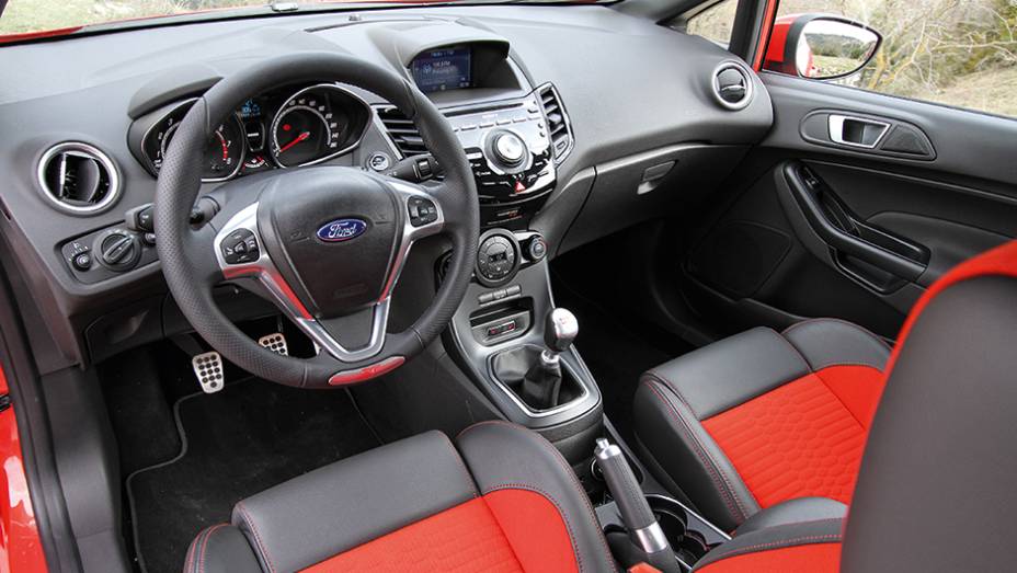 O Fiesta ST n&atilde;o disfar&ccedil;a seu apelo emocional no interior, com mais cromados | <a href="https://beta-develop.quatrorodas.abril.com.br/carros/comparativos/fiesta-st-x-peugeot-208-gti-743718.shtml" rel="migration">Leia mais</a>