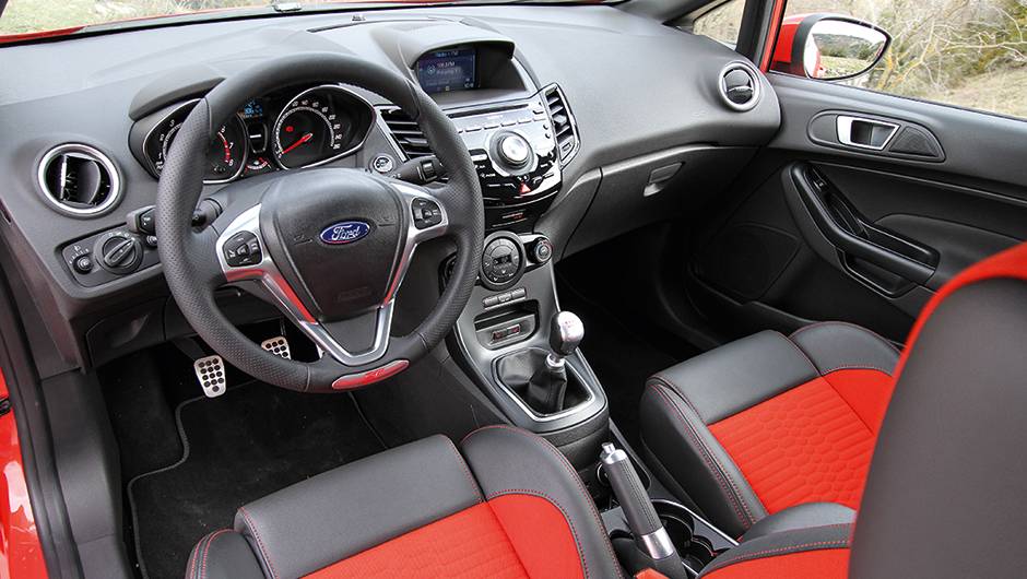 O Fiesta ST n&atilde;o disfar&ccedil;a seu apelo emocional no interior, com mais cromados | <a href="https://beta-develop.quatrorodas.abril.com.br/carros/comparativos/fiesta-st-x-peugeot-208-gti-743718.shtml" rel="migration">Leia mais</a>