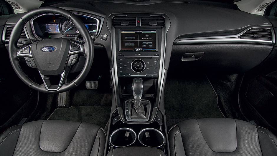 O volante &eacute; multifuncional | <a href="https://beta-develop.quatrorodas.abril.com.br/carros/testes/ford-fusion-hybrid-757087.shtml" rel="migration">Leia mais</a>