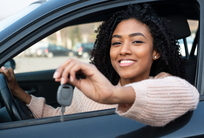 Mulher Preta Sorrindo Segurando chave de carro dentro do veículo. Karvi, plataforma online para vendas de carro.