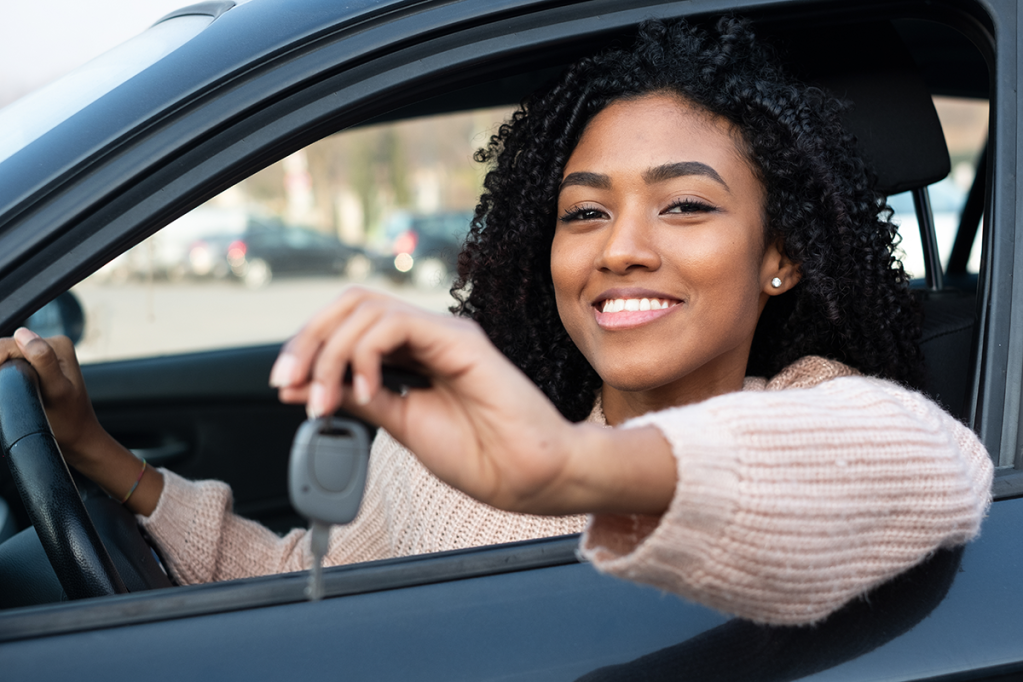 Karvi Plataforma online para vendas de carro Mulher Preta Sorrindo Segurando chave de carro dentro do veículo. Karvi, plataforma online para vendas de carro.