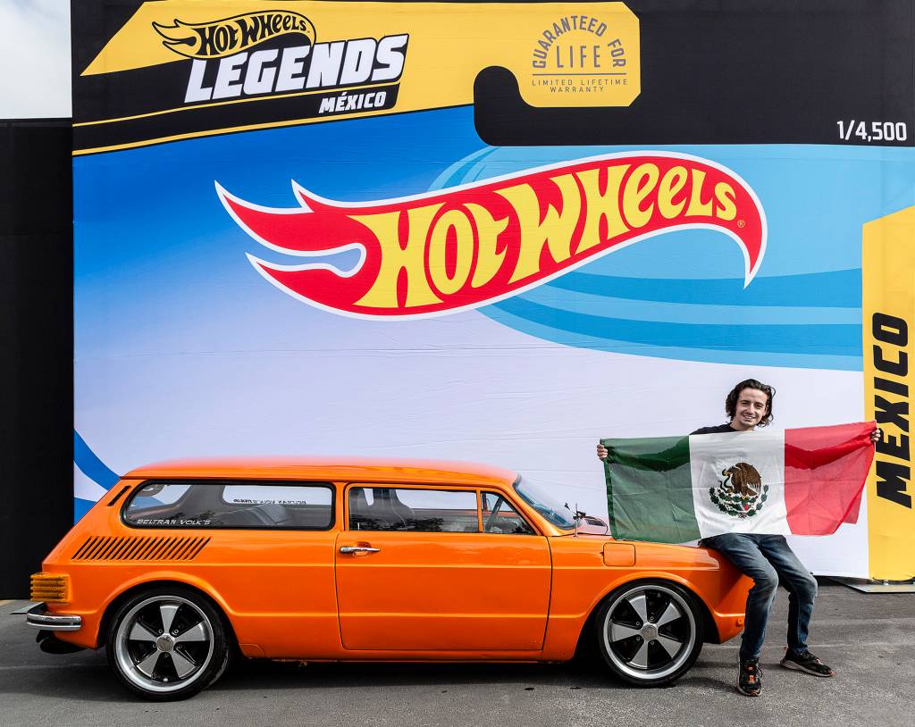 HOT WHEELS LEGENDS 2021 Méxicano posando com a bandeira do país e seu modelo laranja visto de lado