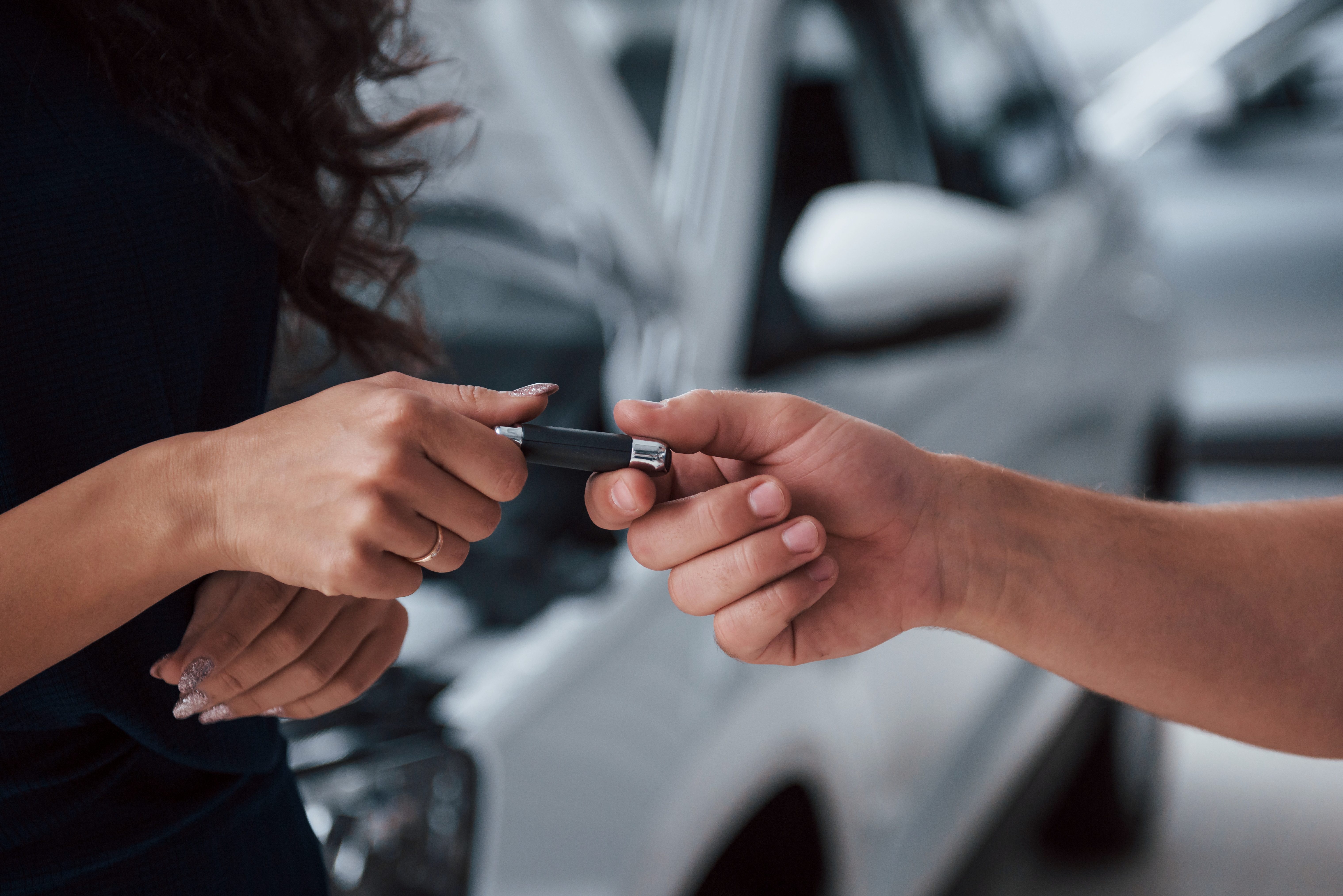 Side view. Woman in the auto salon with employee taking her repaired car back