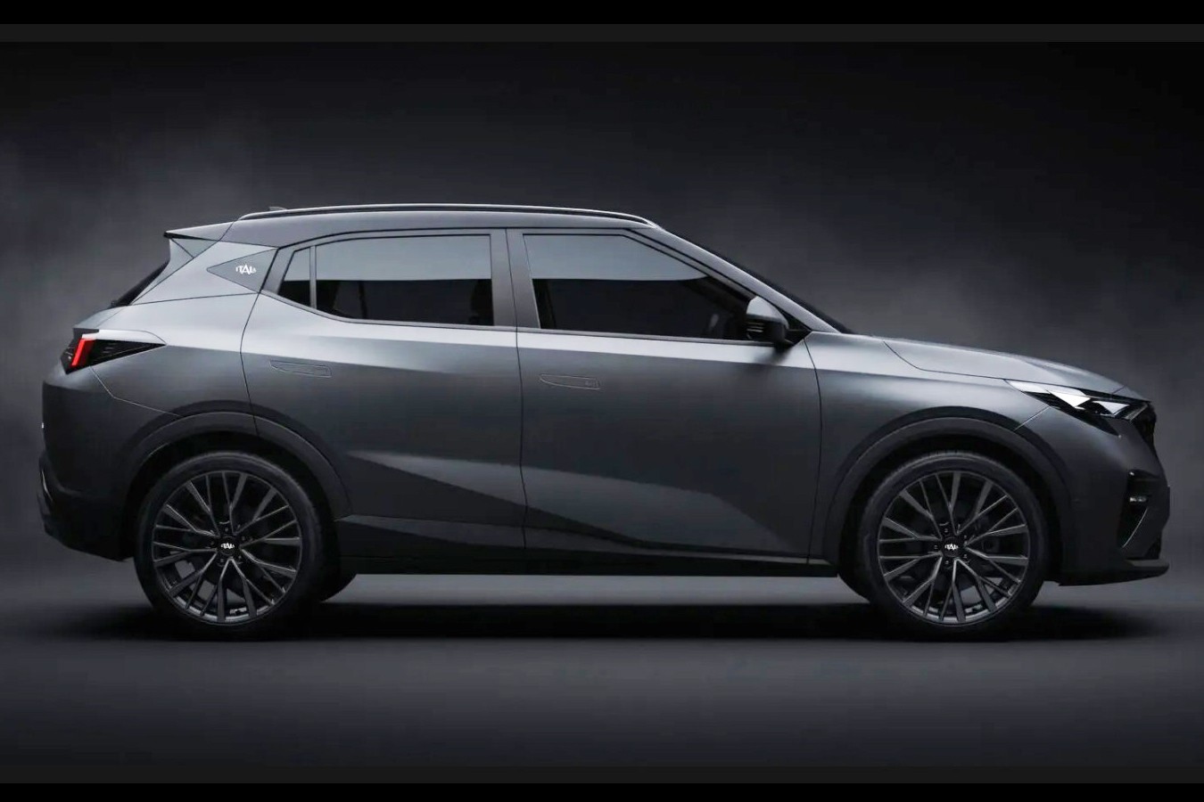 SUV cinza escuro, com teto e rodas pretas, visto de perfil em um fundo escuro. Far&oacute;is e lanternas traseiras acesas, destacando o design moderno do ve&iacute;culo