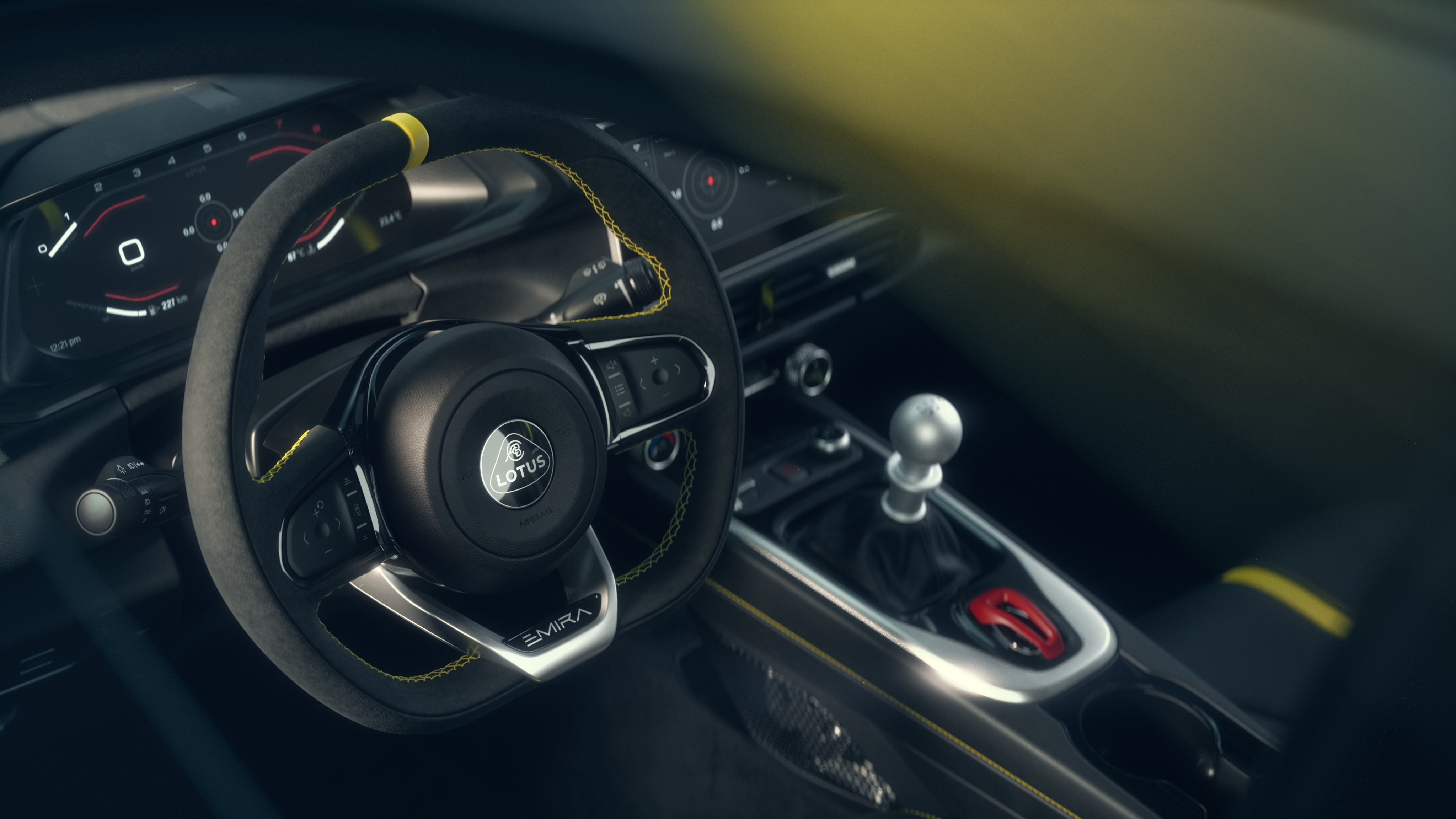Interior de um carro esportivo Lotus Emira, mostrando o volante revestido em camur&ccedil;a com costura amarela, o painel digital e o c&acirc;mbio manual com manopla prateada e detalhe vermelho no console central