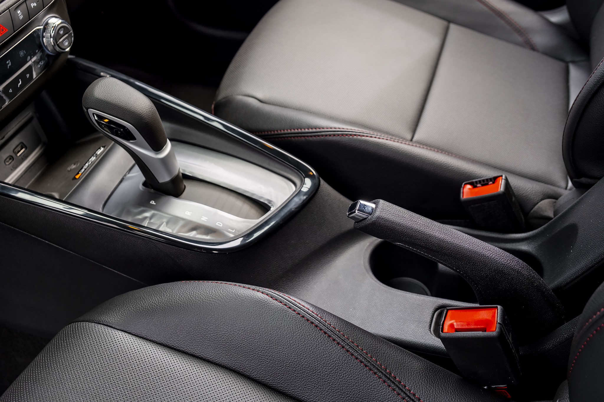 Interior de carro com c&acirc;mbio autom&aacute;tico, freio de m&atilde;o e bancos de couro preto com costura vermelha