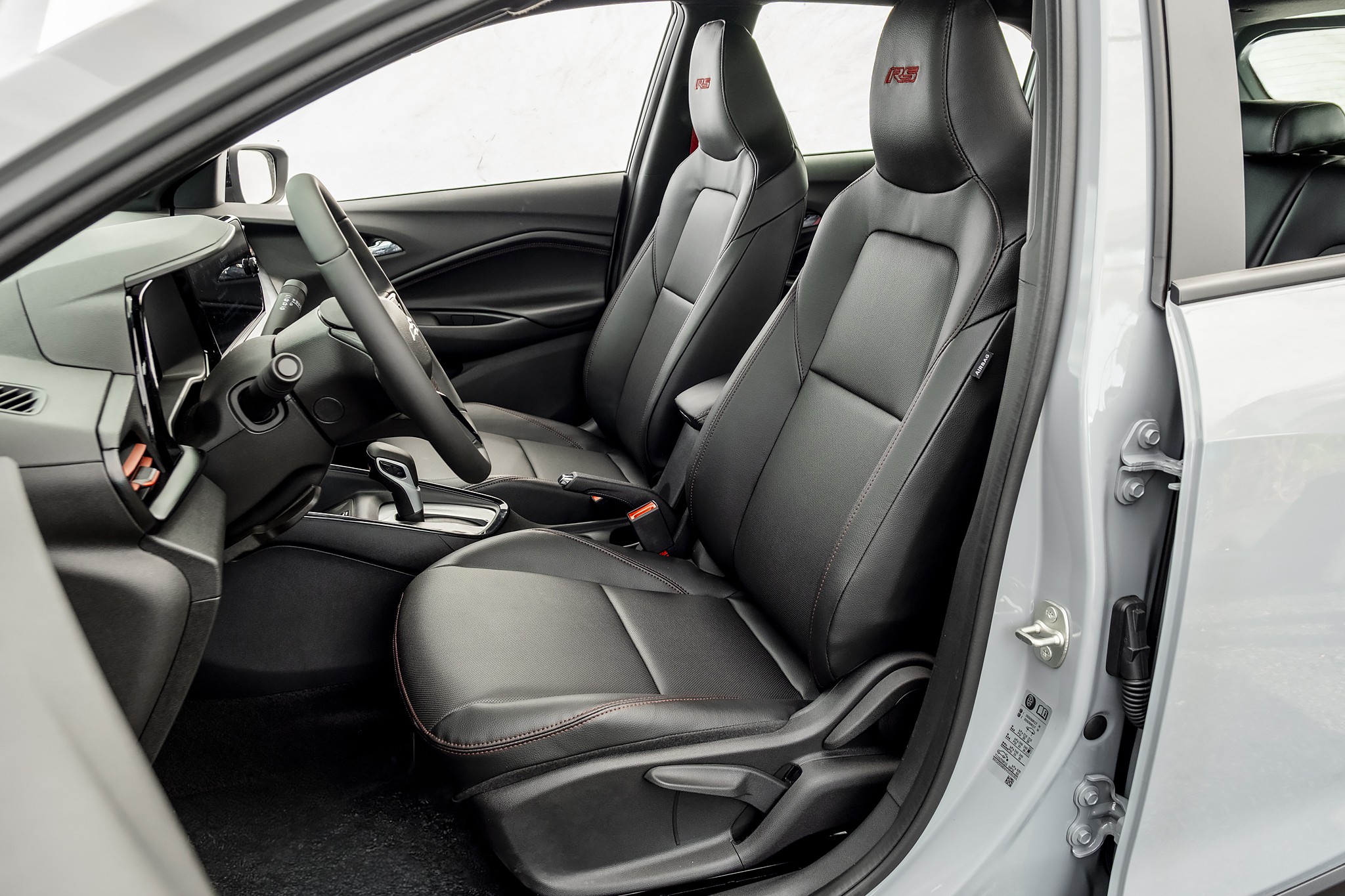 Interior de carro cinza com bancos de couro preto e costura vermelha, volante e painel escuros, c&acirc;mbio autom&aacute;tico e emblemas 