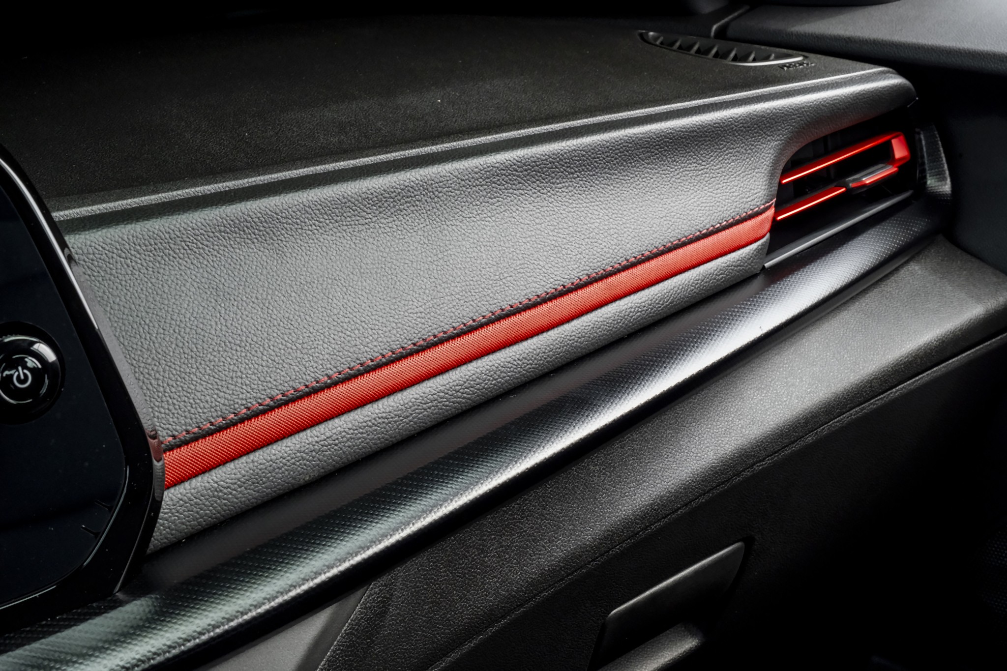 Interior de carro com painel cinza-escuro texturizado, faixa horizontal vermelha costurada e sa&iacute;da de ar com ilumina&ccedil;&atilde;o vermelha