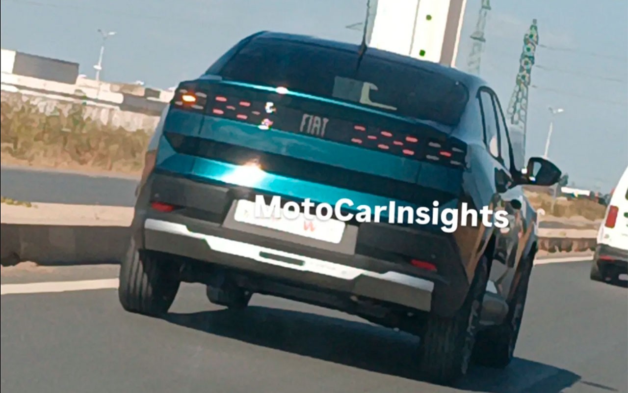 Traseira de um carro Fiat azul-petr&oacute;leo, com lanternas horizontais de LED e para-choque preto com detalhe prateado, em uma estrada sob luz solar