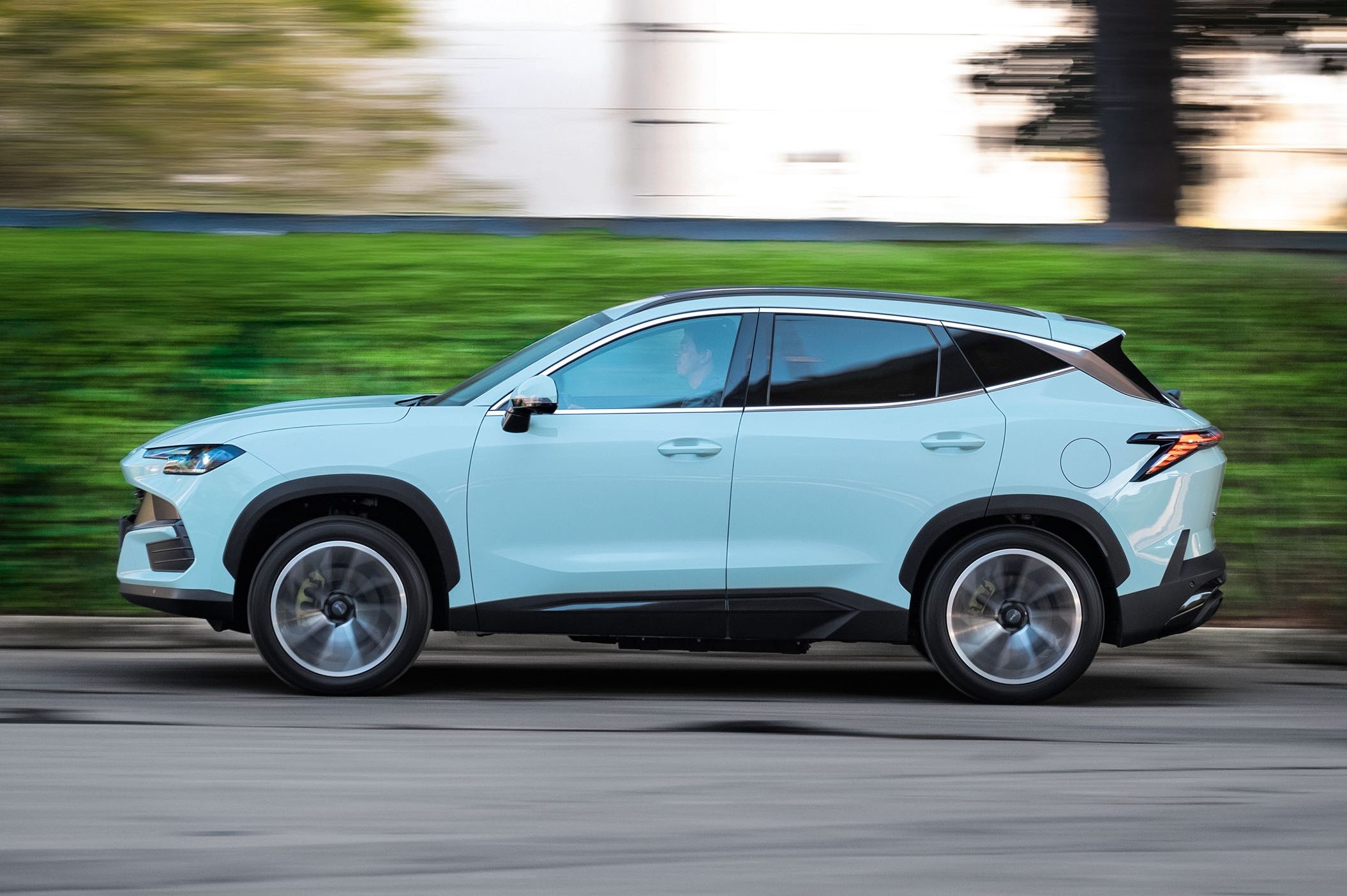 SUV azul-claro em movimento, visto de lado, com o fundo borrado por efeito de velocidade. O ve&iacute;culo tem detalhes em preto nas caixas de roda e na parte inferior da carroceria, e rodas de liga leve prateadas.