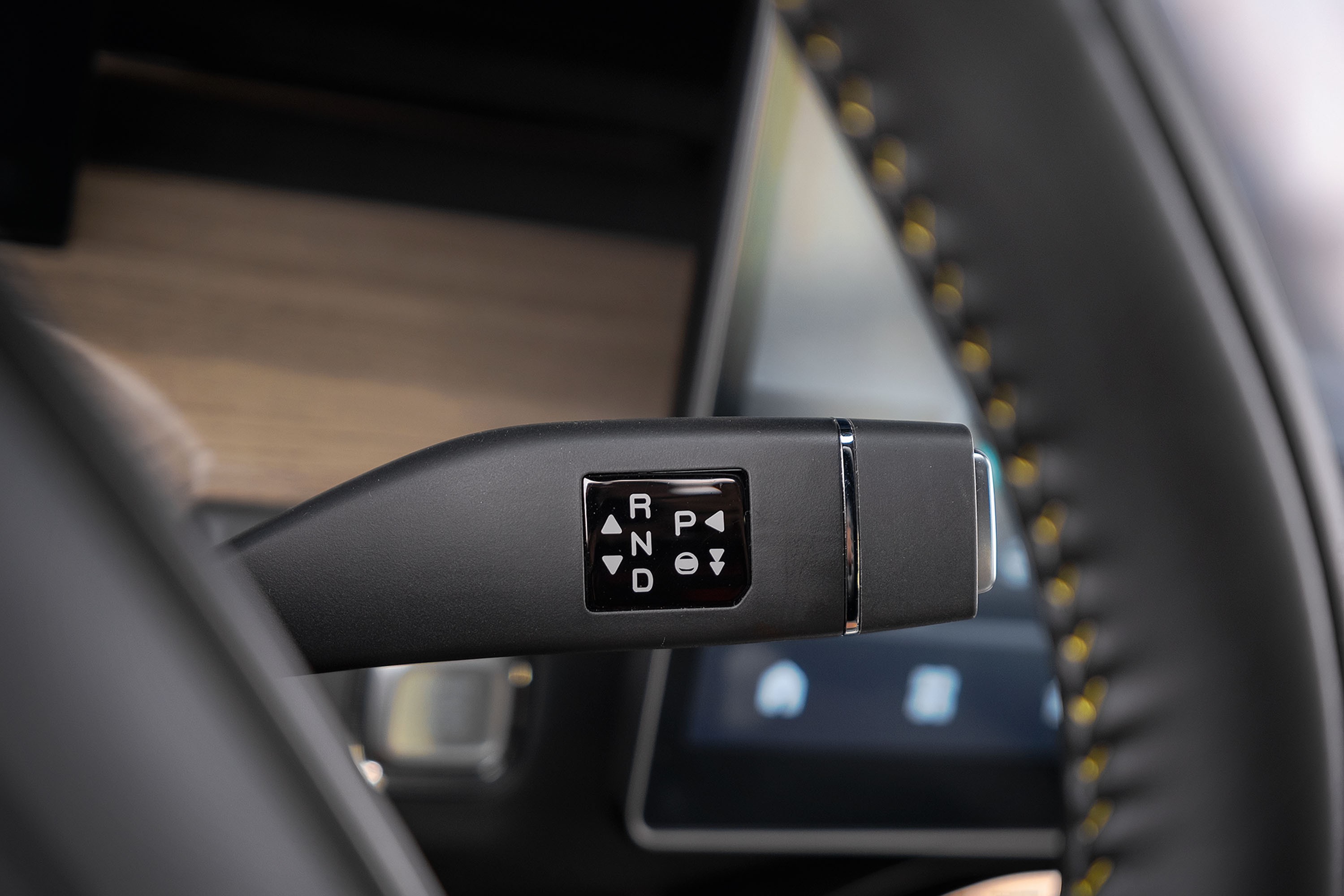 Alavanca de c&acirc;mbio autom&aacute;tica preta com bot&otilde;es para R, N, D e P, al&eacute;m de setas para cima e para baixo, no interior de um carro moderno com volante de couro e costura amarela