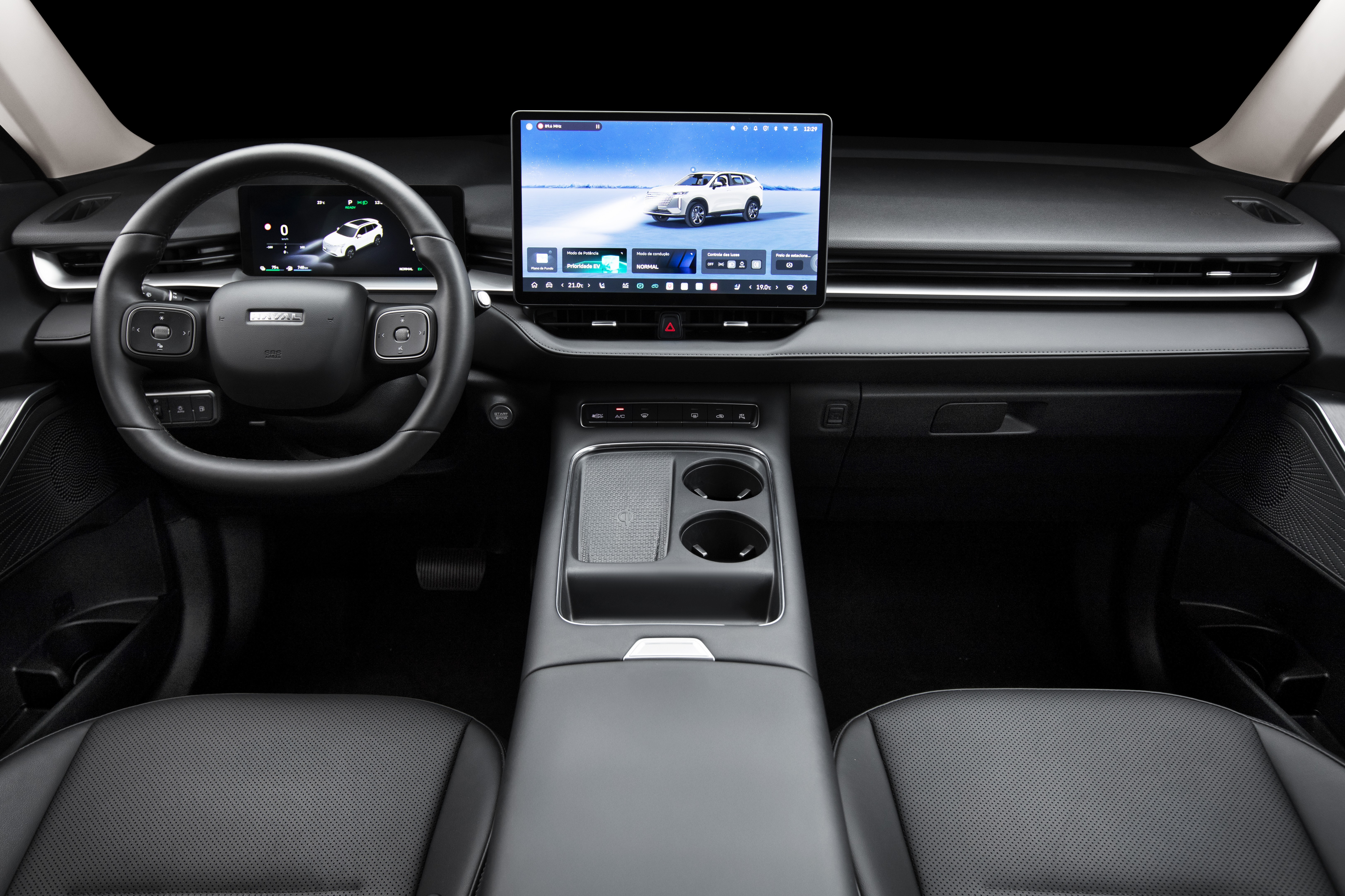 Interior de um carro moderno com painel escuro, volante multifuncional e duas telas digitais. A tela central exibe um SUV branco em uma paisagem nevada, enquanto a tela menor atr&aacute;s do volante mostra um mapa com o mesmo ve&iacute;culo. H&aacute; um console central com porta-copos e apoio de bra&ccedil;o, e bancos de couro pretos vis&iacute;veis