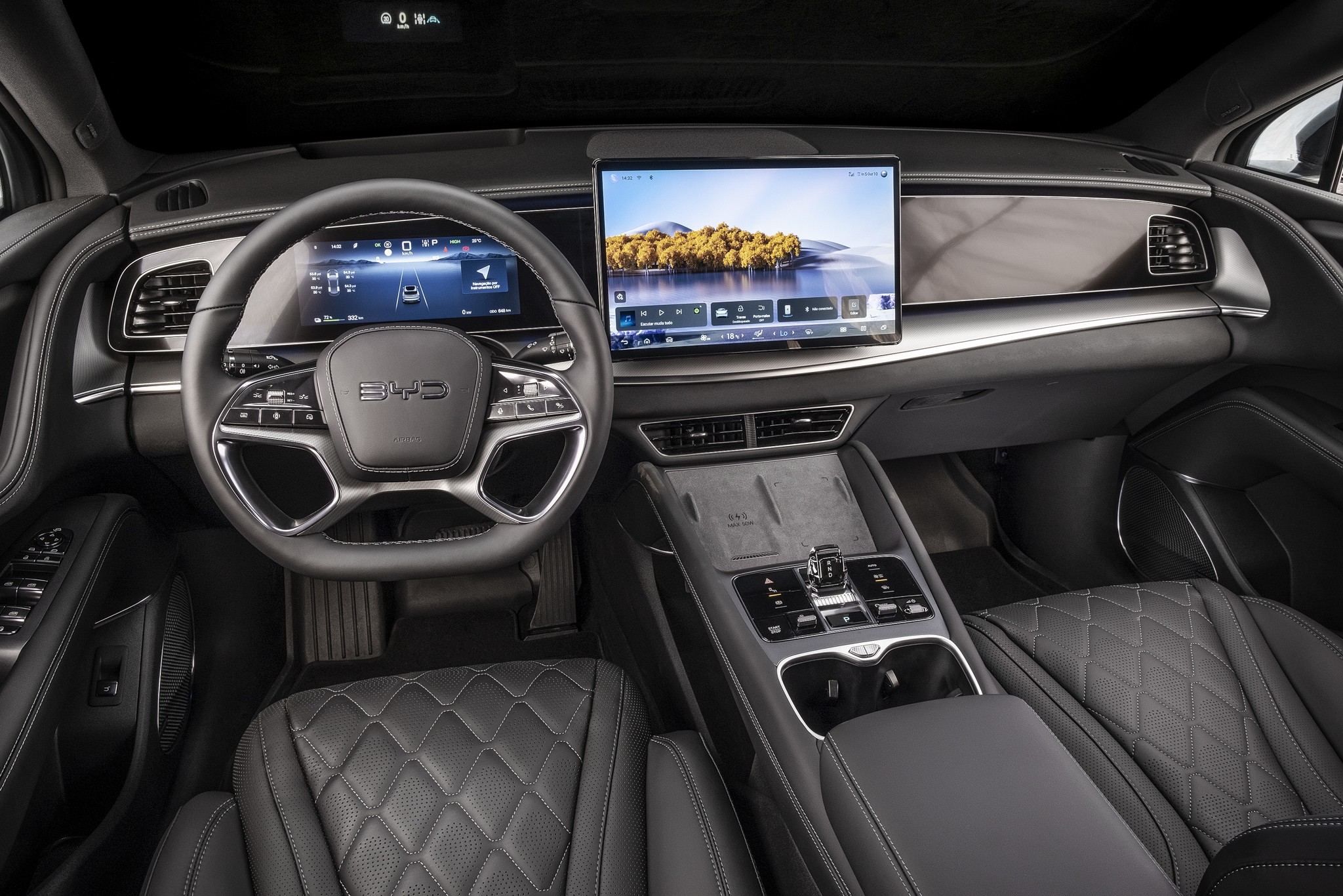 Interior de um carro moderno com volante multifuncional preto e prateado, painel digital exibindo informa&ccedil;&otilde;es de dire&ccedil;&atilde;o e uma grande tela central mostrando uma paisagem com &aacute;rvores e &aacute;gua. Os bancos de couro preto t&ecirc;m costura em formato de diamante, e o console central possui bot&otilde;es de controle e porta-copos.