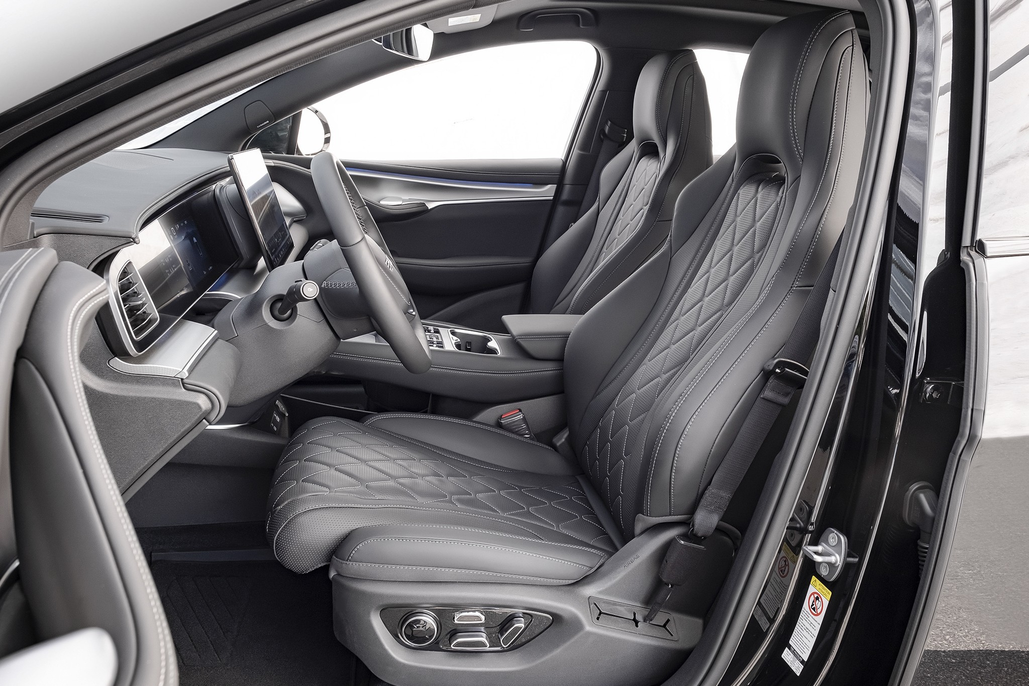 Interior de carro moderno com bancos de couro cinza escuro e costura em losango, volante multifuncional, painel digital e tela central. A porta do motorista est&aacute; aberta, revelando o acabamento preto e detalhes cromados. O ambiente &eacute; sofisticado e tecnol&oacute;gico