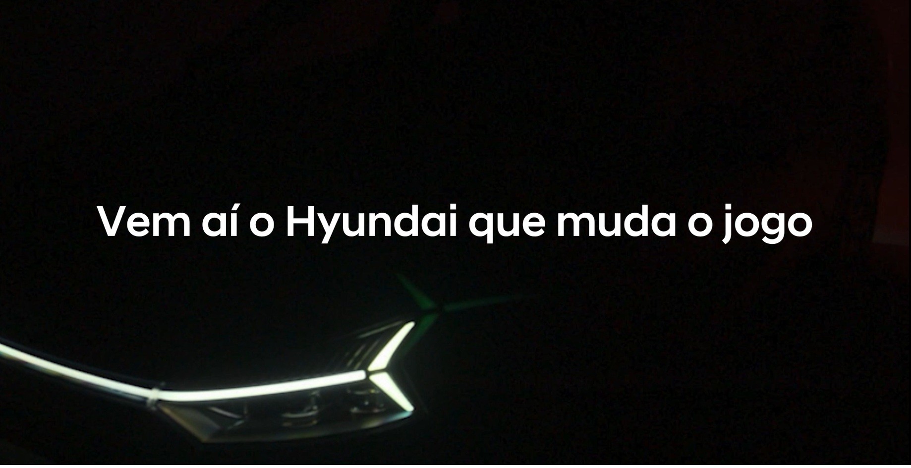 Texto branco Vem a&iacute; o Hyundai que muda o jogo sobre fundo preto, com detalhes luminosos de um carro futurista na parte inferior