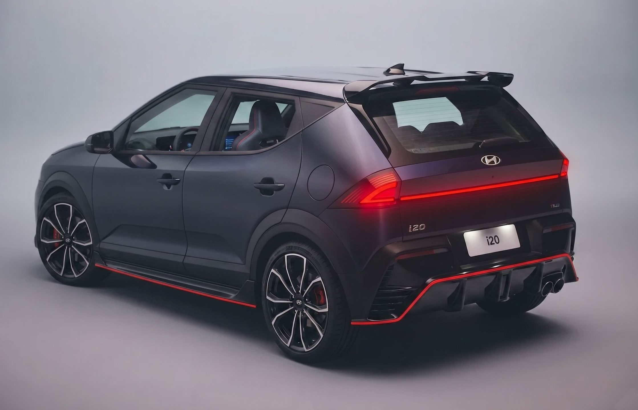 Carro Hyundai i20 N cinza-escuro, visto de traseira lateral, com detalhes em vermelho, rodas esportivas e aerof&oacute;lio, em est&uacute;dio com fundo cinza