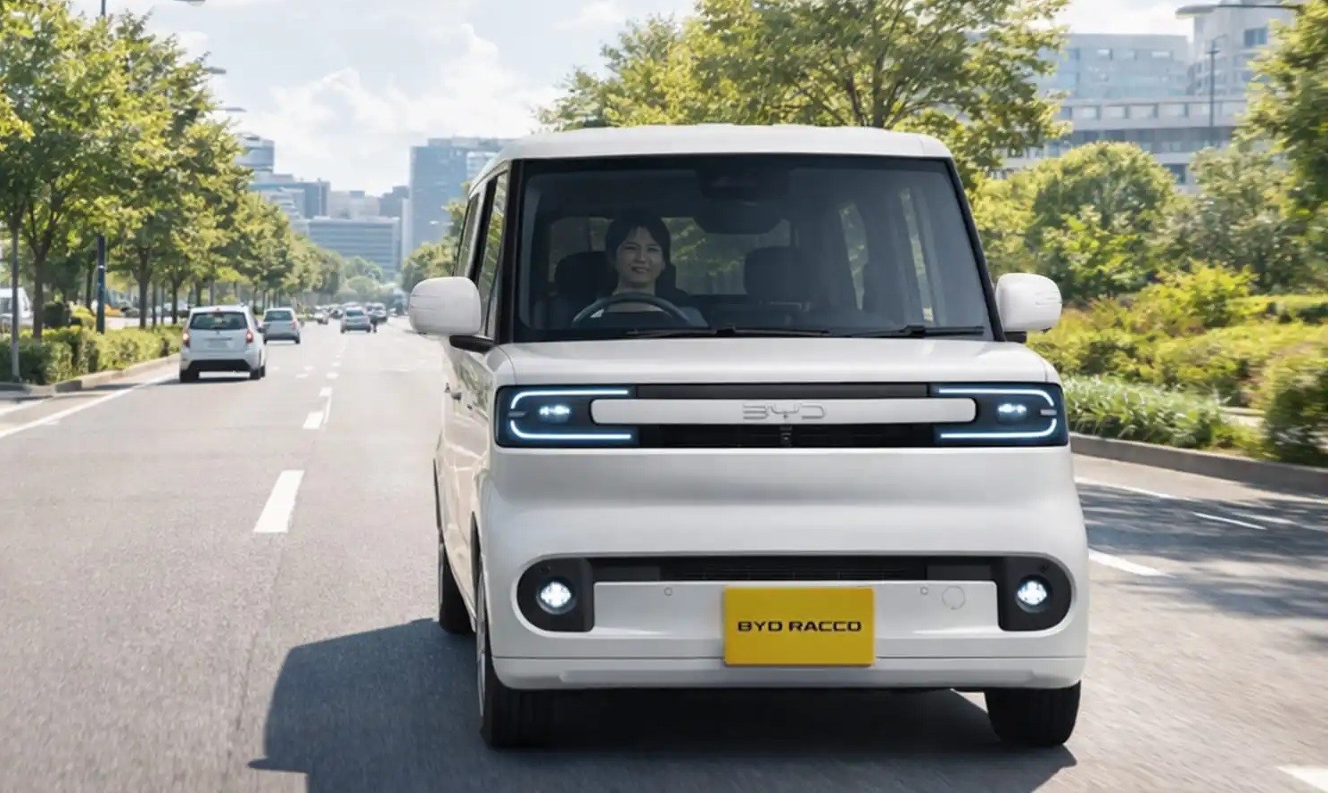 Carro el&eacute;trico BYD Racco branco, compacto e quadrado, com uma mulher sorrindo ao volante, trafegando em uma avenida arborizada com outros ve&iacute;culos ao fundo