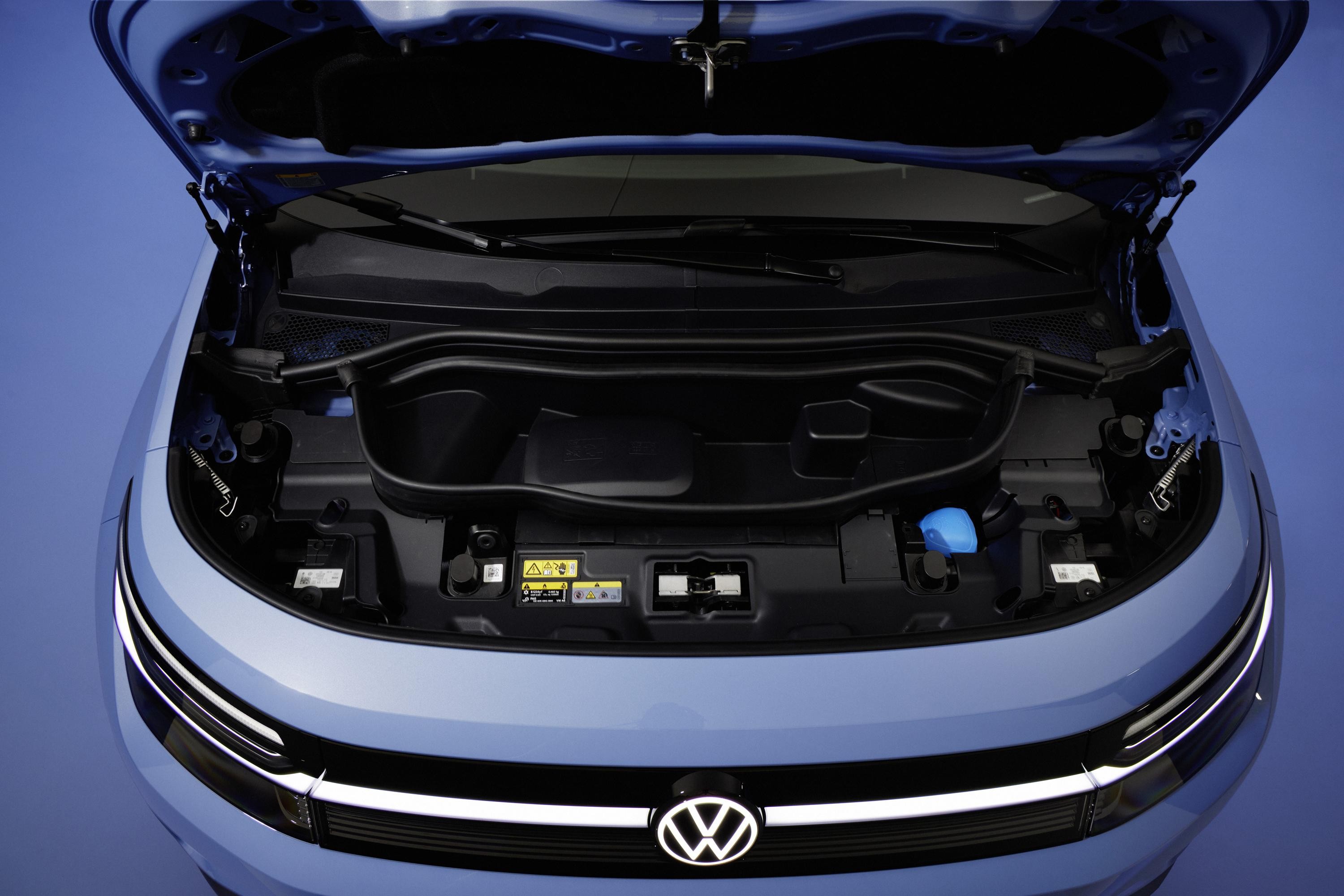 Cap&ocirc; azul de um carro el&eacute;trico Volkswagen aberto, revelando um compartimento de armazenamento frontal vazio, com o logotipo da marca iluminado na grade inferior