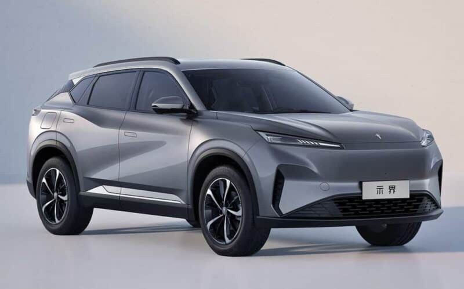 SUV el&eacute;trico cinza-chumbo, com design moderno e linhas fluidas, visto de frente e lateralmente. Possui far&oacute;is finos, grade frontal fechada e rodas de liga leve com detalhes pretos e prateados. Um emblema chin&ecirc;s est&aacute; na placa dianteira