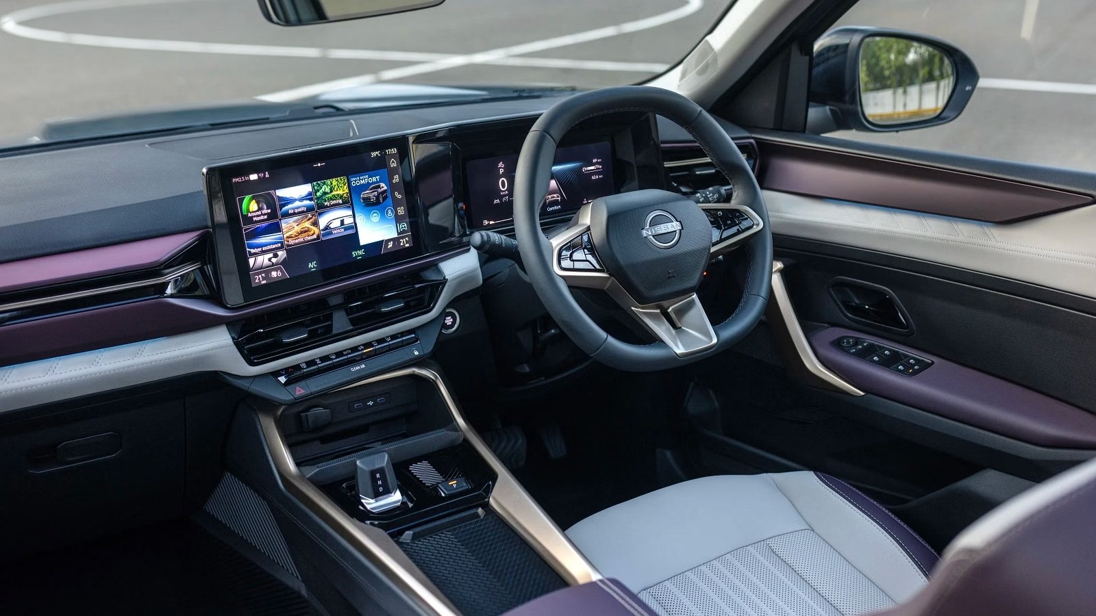 Interior de um carro moderno com painel cinza e detalhes em roxo. Volante escuro com o logo Nissan, tela multim&iacute;dia exibindo aplicativos e um assento do passageiro em tons de cinza e branco. O retrovisor lateral reflete &aacute;rvores e o c&eacute;u.