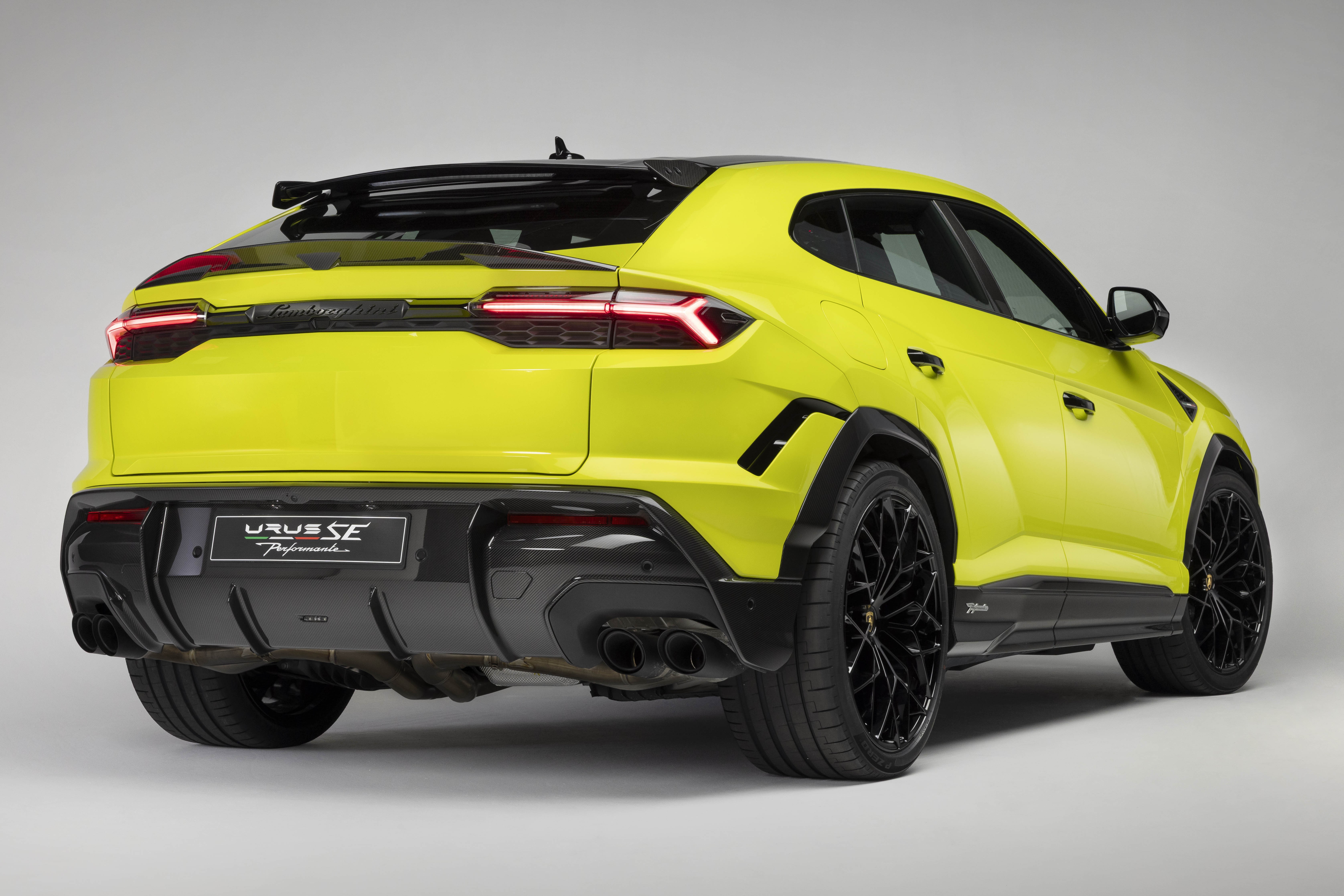 SUV Lamborghini Urus SE Performante amarelo-lim&atilde;o, visto de tr&aacute;s e lateral, com lanternas traseiras acesas, difusor e escapamento duplos pretos, rodas pretas e detalhes aerodin&acirc;micos pretos
