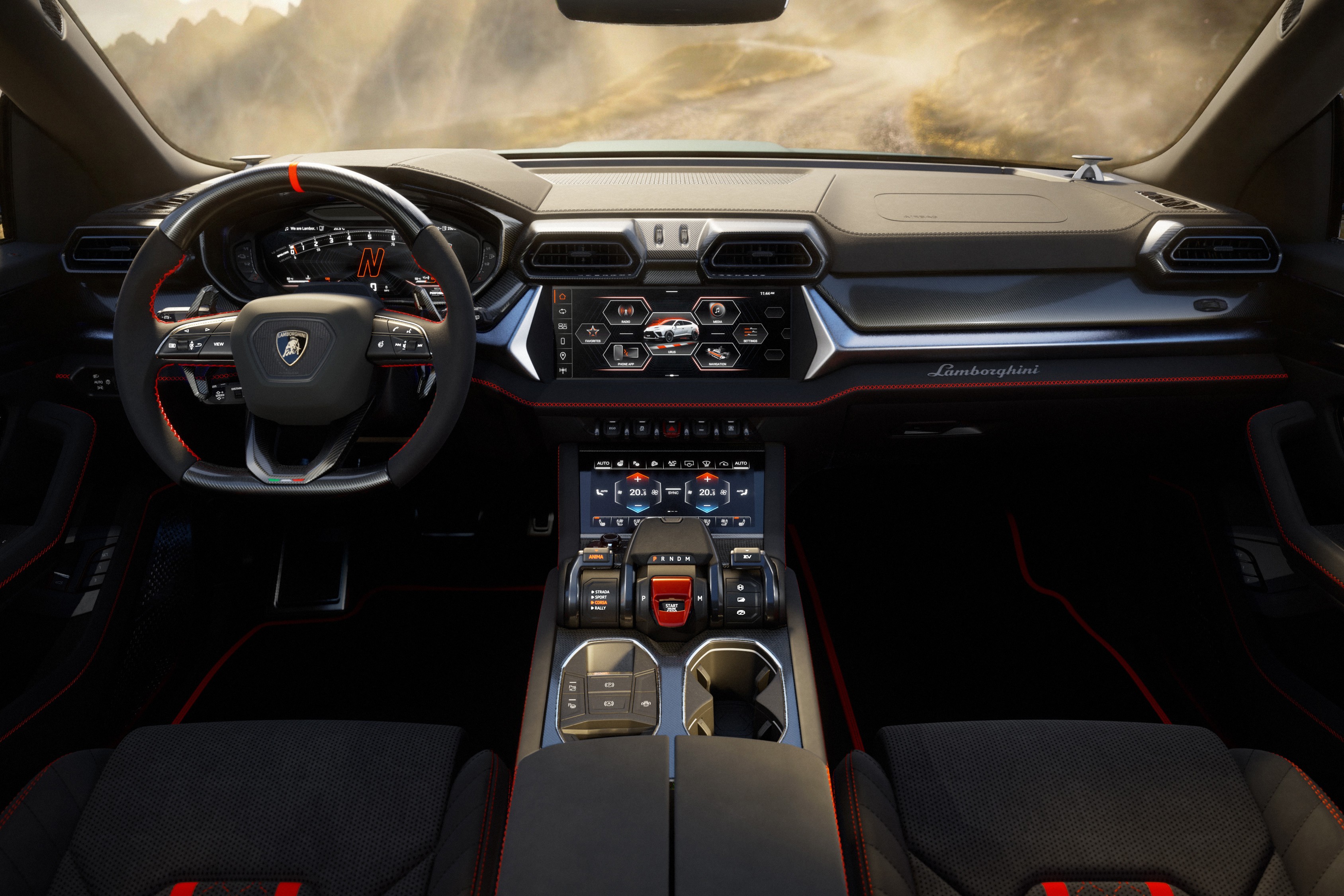 Interior de um Lamborghini Urus, com volante esportivo preto e detalhes vermelhos, painel digital, duas telas sens&iacute;veis ao toque no console central e bancos de couro preto com costuras vermelhas. Ao fundo, uma paisagem montanhosa emba&ccedil;ada