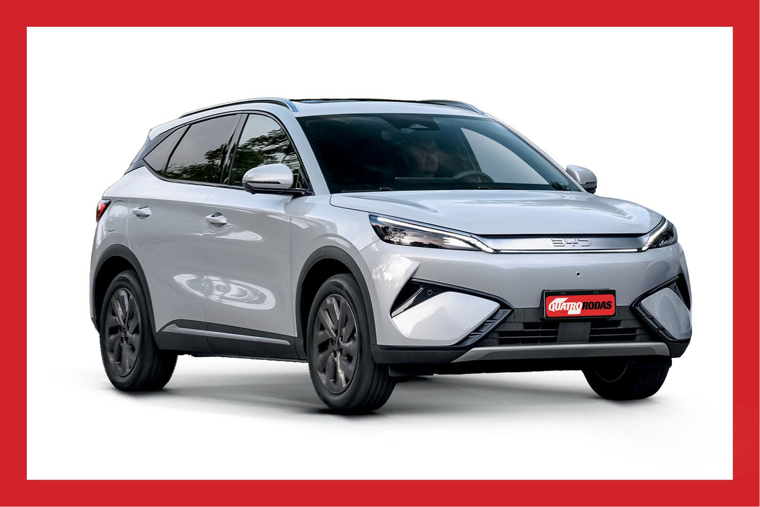 SUV BYD Song Plus DM-i cinza claro, visto de frente e levemente de lado, com o logotipo QUATRO RODAS na placa dianteira, em fundo branco