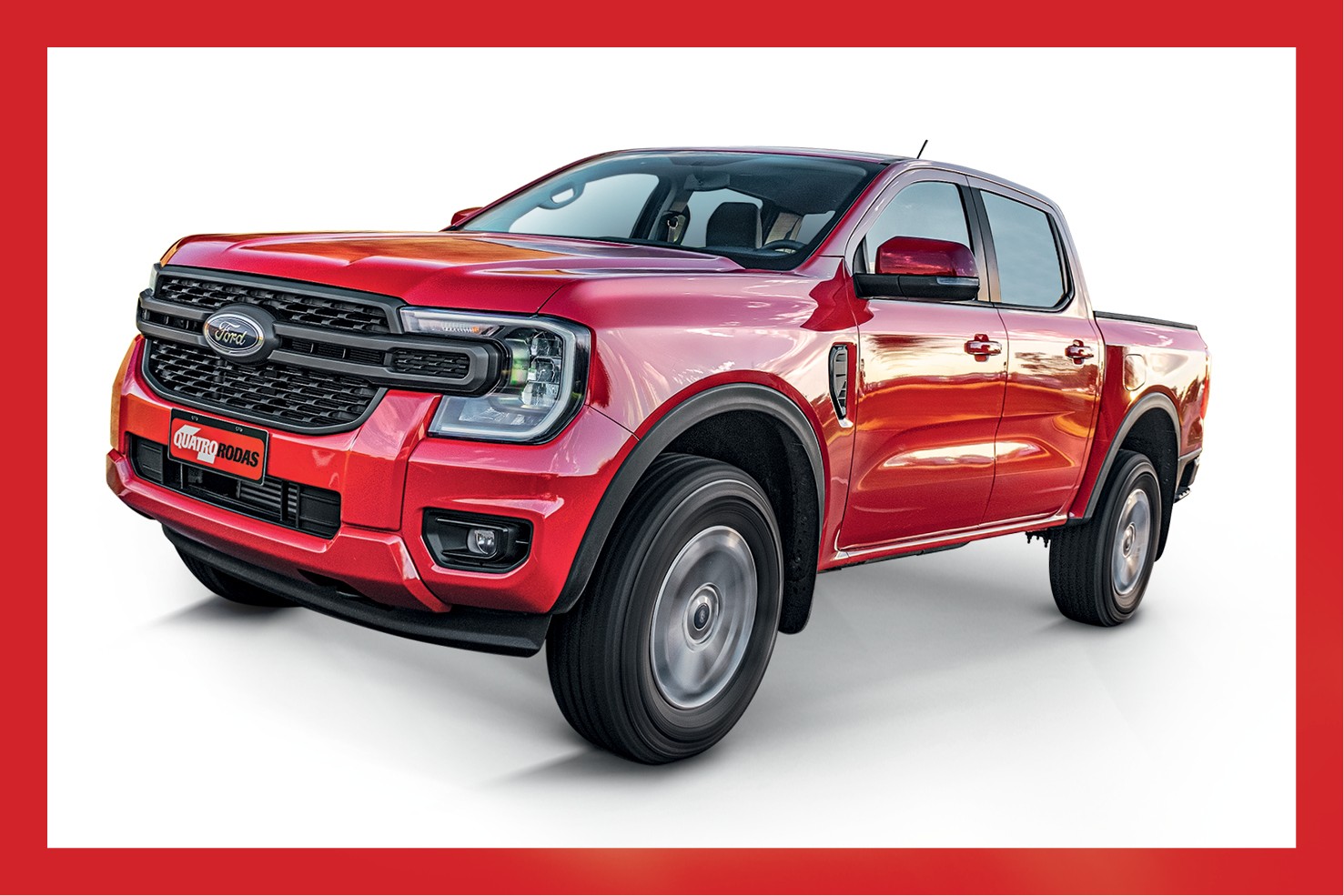 Picape Ford Ranger vermelha, modelo 2023, vista de frente e levemente de lado, com a grade frontal preta e o logotipo da Ford em destaque. O para-choque dianteiro tem far&oacute;is de neblina e uma placa vermelha com o texto QUATRO RODAS em branco. O ve&iacute;culo est&aacute; sobre um fundo branco, com uma borda vermelha ao redor da imagem