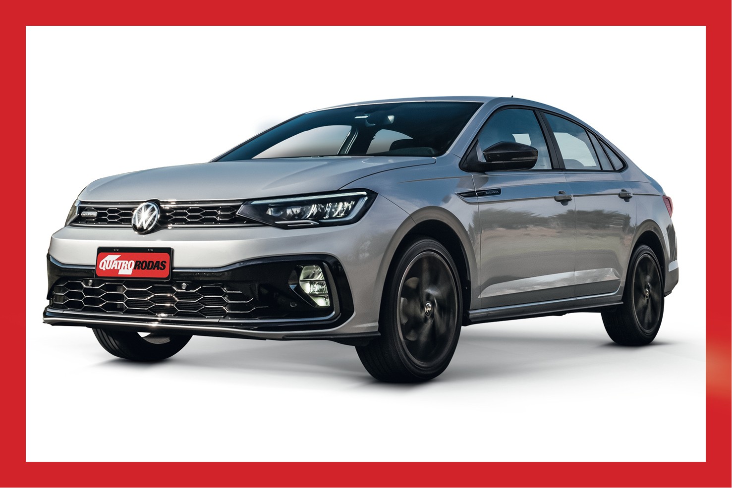 Carro sedan cinza-prateado, modelo Volkswagen Virtus, visto de frente e lateralmente, com rodas escuras em movimento e placa vermelha QUATRO RODAS na frente, sobre fundo branco