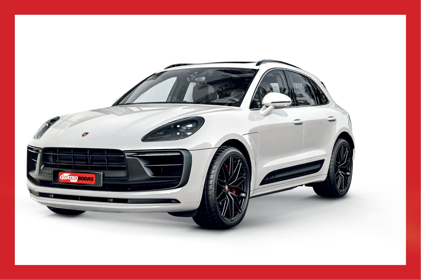 SUV Porsche Macan branco, visto de frente e lateralmente, com rodas pretas e detalhes escuros na parte inferior da carroceria, sobre fundo branco. No para-choque dianteiro, uma placa vermelha com o texto QUATRO RODAS em branco