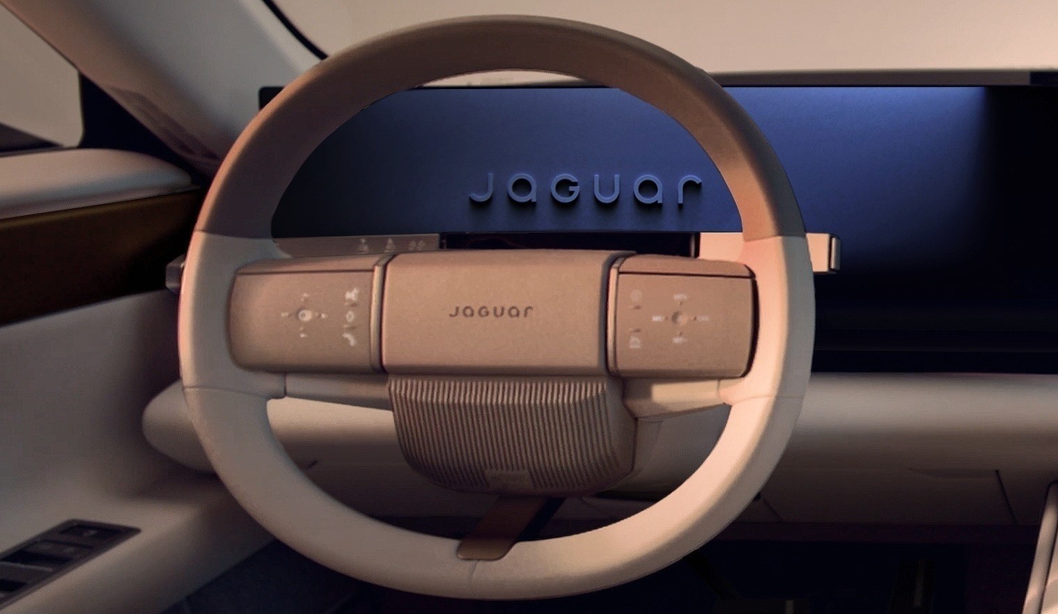 Interior de um carro moderno, com volante bege claro e painel digital escuro exibindo o nome Jaguar em relevo. O volante possui bot&otilde;es de controle e o nome Jaguar gravado no centro, com detalhes canelados na parte inferior. A ilumina&ccedil;&atilde;o suave destaca o design futurista do ve&iacute;culo