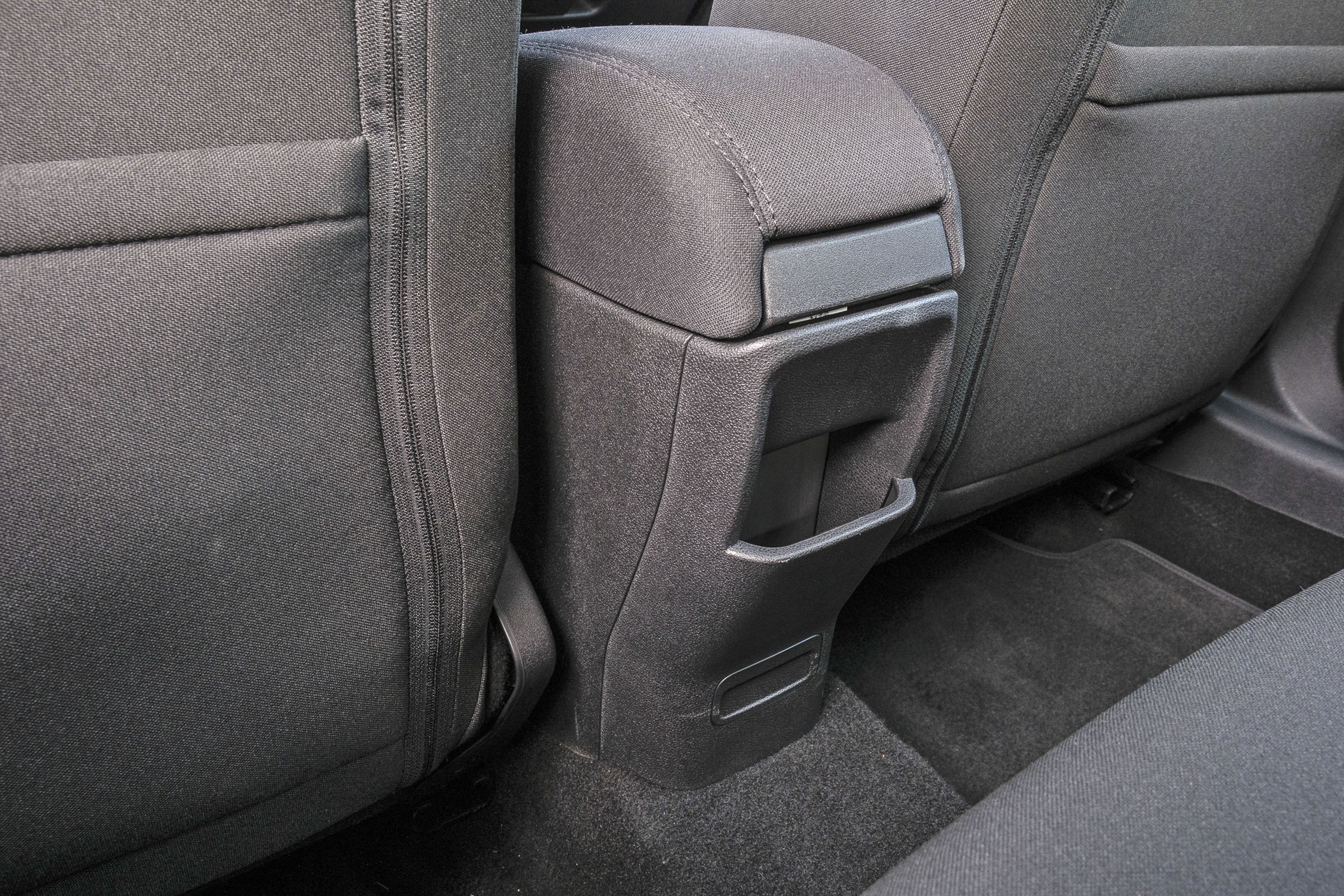 Console central de um carro, cinza escuro, com porta-objetos e apoio de bra&ccedil;o estofado, entre dois bancos traseiros de tecido cinza