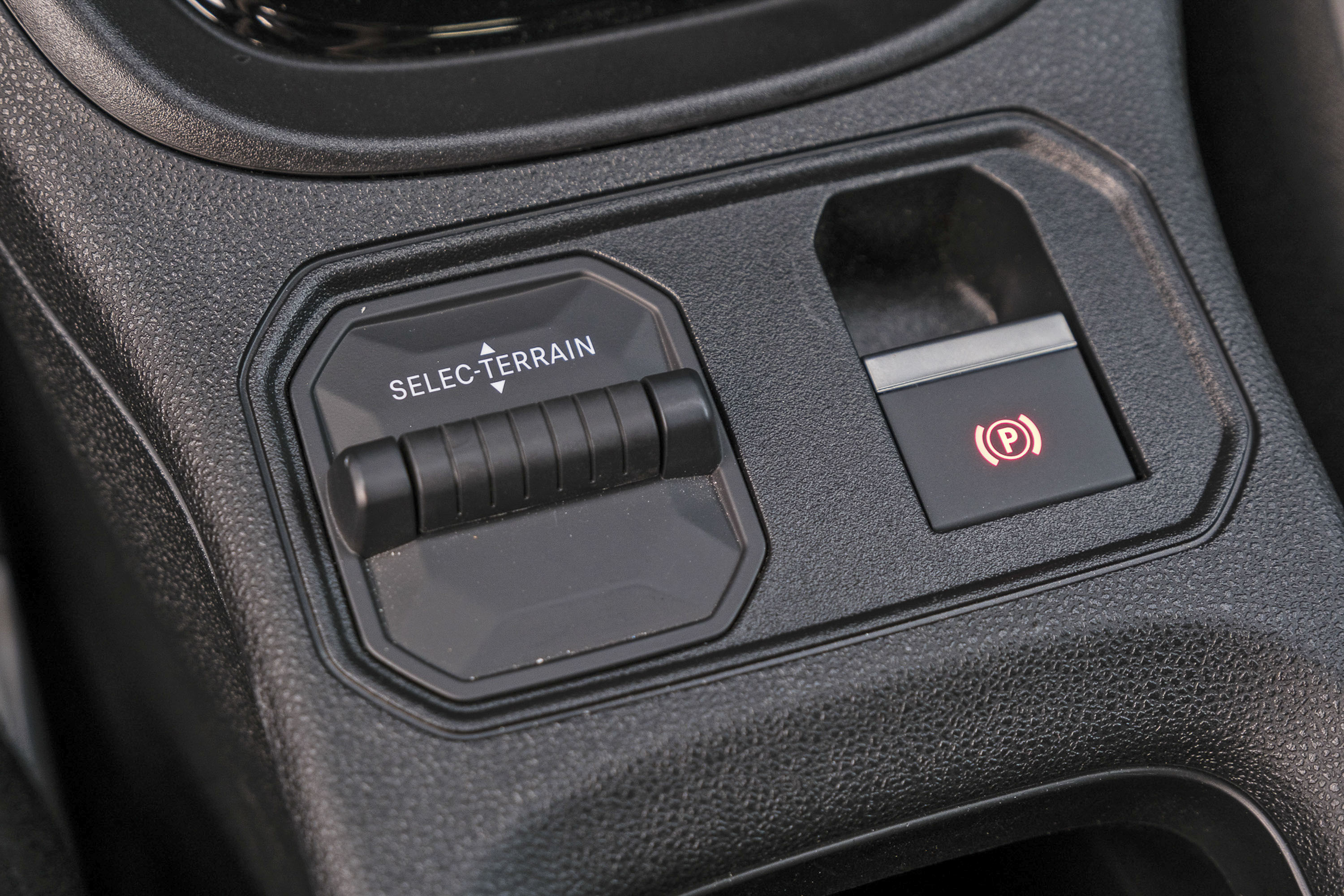 Painel de controle automotivo com seletor de terreno SELEC-TERRAIN e bot&atilde;o do freio de estacionamento eletr&ocirc;nico aceso em vermelho