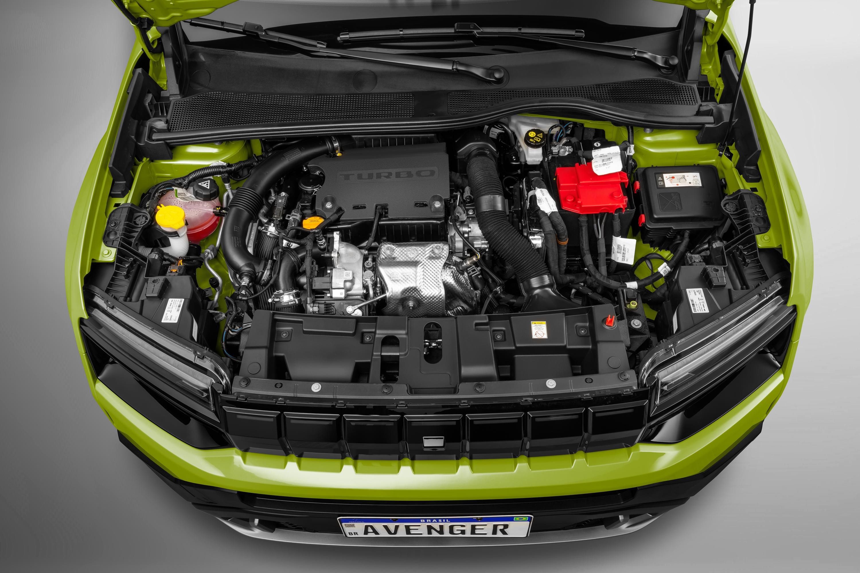 Motor de um carro verde-lim&atilde;o visto de cima, com o cap&ocirc; aberto. Componentes como o motor turbo, bateria vermelha e reservat&oacute;rios de fluidos s&atilde;o vis&iacute;veis, com a grade frontal preta e a placa AVENGER na parte inferior