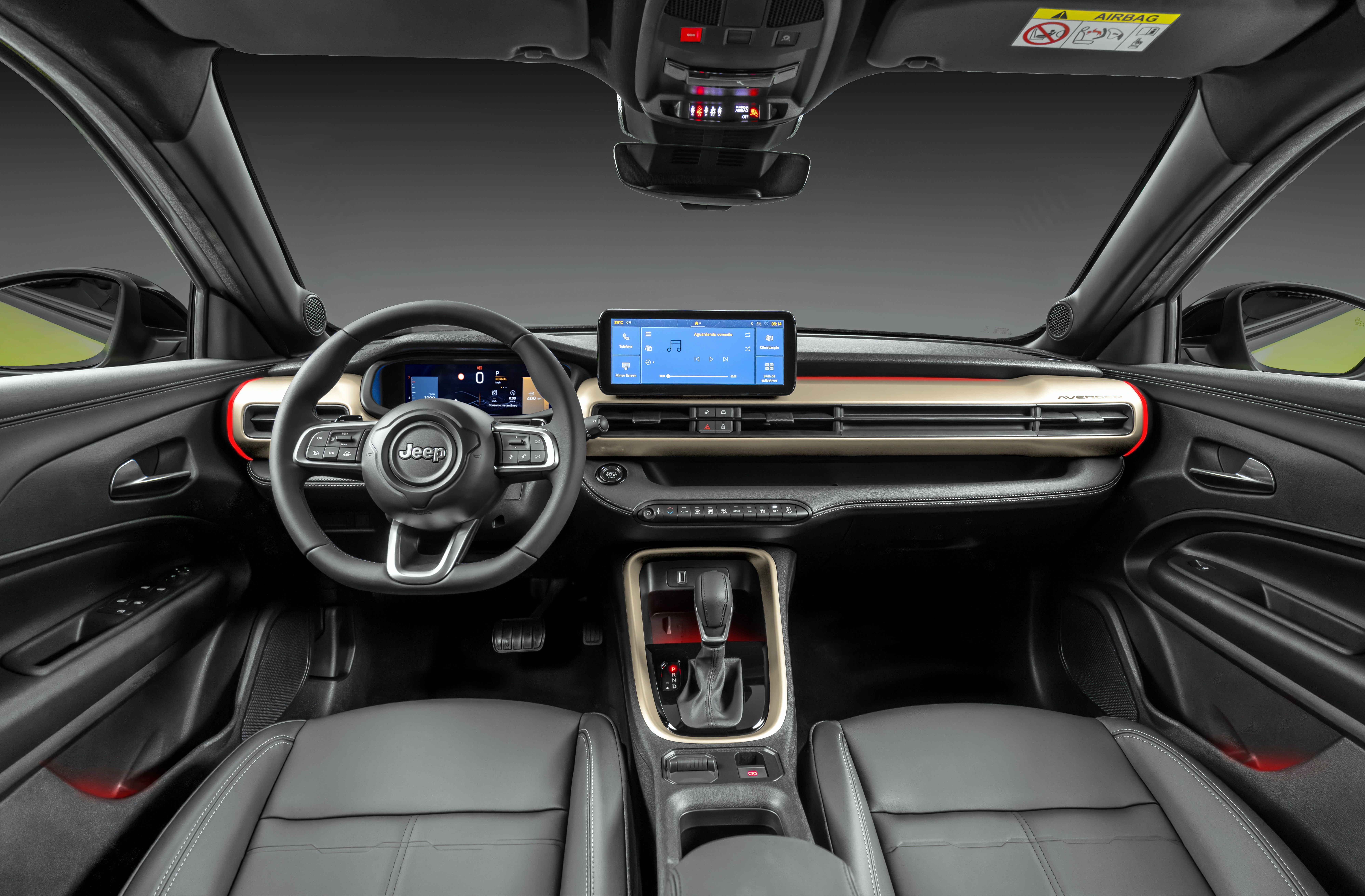 Interior de um carro Jeep com bancos de couro cinza, volante multifuncional e painel com detalhes dourados. Uma tela central exibe um sistema de navega&ccedil;&atilde;o e m&iacute;dia, enquanto o console tem c&acirc;mbio autom&aacute;tico e porta-objetos.