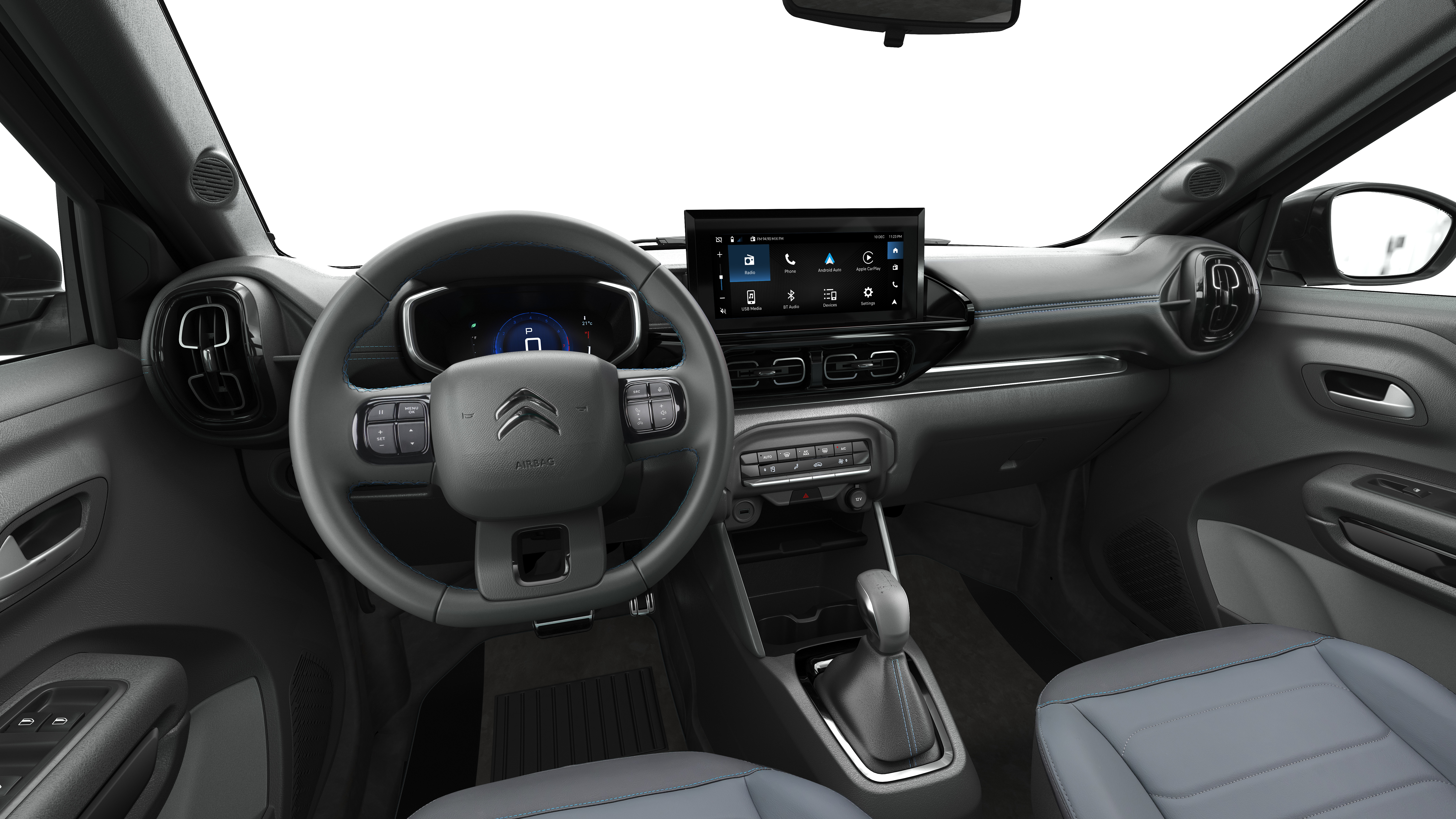 Interior de um carro moderno, com volante multifuncional cinza escuro e o logotipo da Citro&euml;n ao centro. O painel possui uma tela multim&iacute;dia sens&iacute;vel ao toque exibindo &iacute;cones de aplicativos, e logo abaixo, bot&otilde;es de controle. O c&acirc;mbio autom&aacute;tico est&aacute; vis&iacute;vel no console central. Os bancos s&atilde;o cinza claro, e o ambiente geral &eacute; de um ve&iacute;culo novo e tecnol&oacute;gico