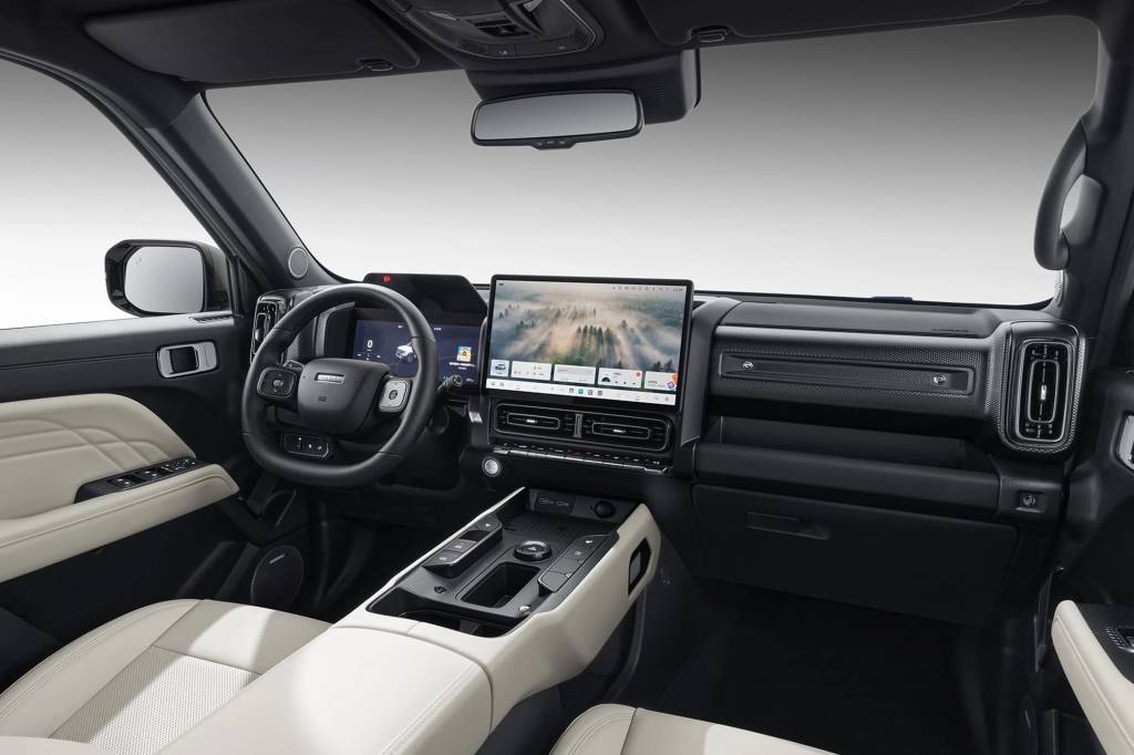Interior de um carro moderno com bancos e detalhes das portas em couro bege claro, contrastando com o painel e volante pretos. Uma grande tela central exibe uma paisagem de floresta com neblina, e o volante tem bot&otilde;es de controle integrados. O console central possui bot&otilde;es e um seletor girat&oacute;rio.