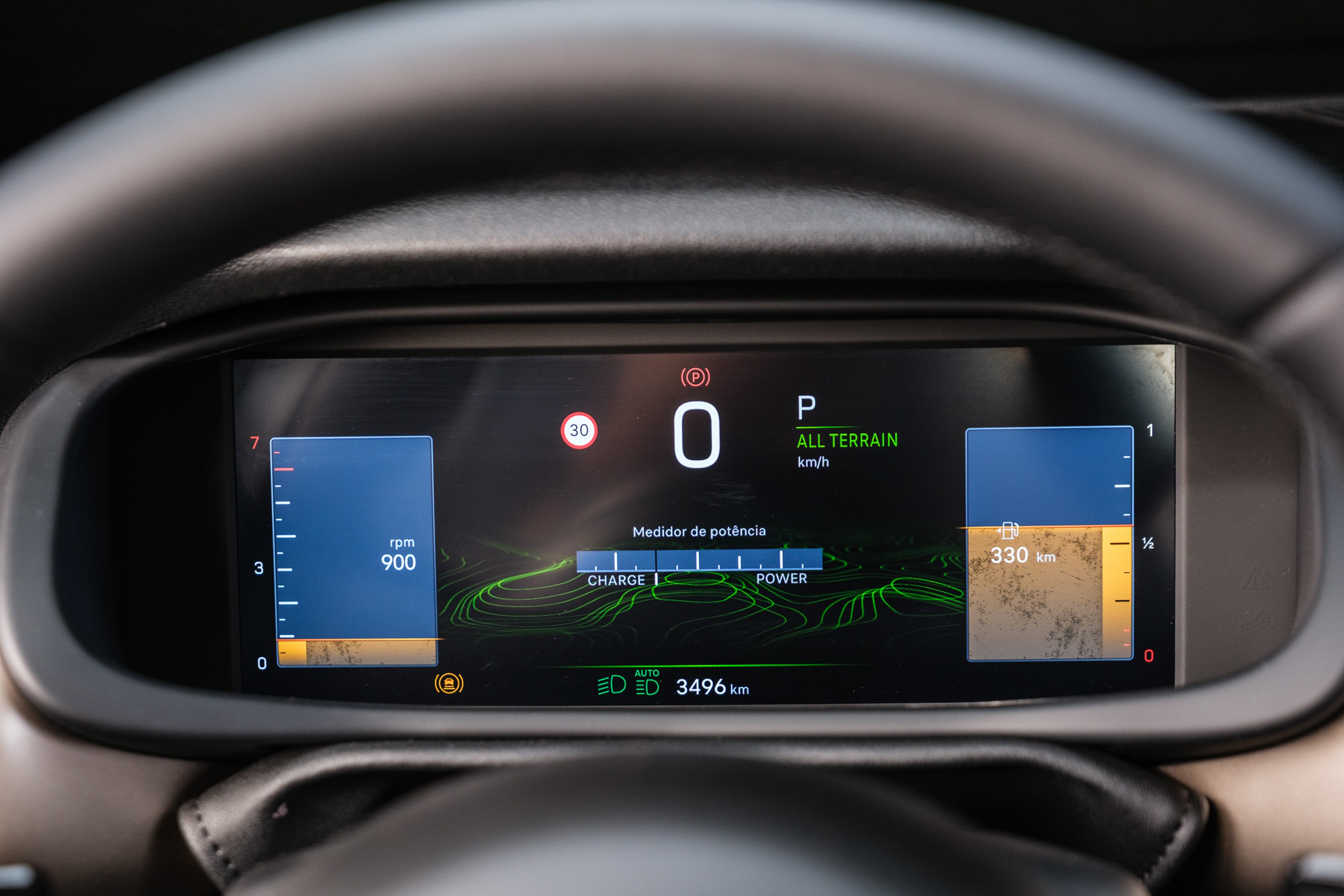 Painel digital de carro com veloc&iacute;metro marcando 0, marcha P (Park) e modo All Terrain. &Agrave; esquerda, conta-giros em 900 rpm; ao centro, medidor de pot&ecirc;ncia com barras de carga e for&ccedil;a; &agrave; direita, autonomia de 330 km. O hod&ocirc;metro registra 3496 km.