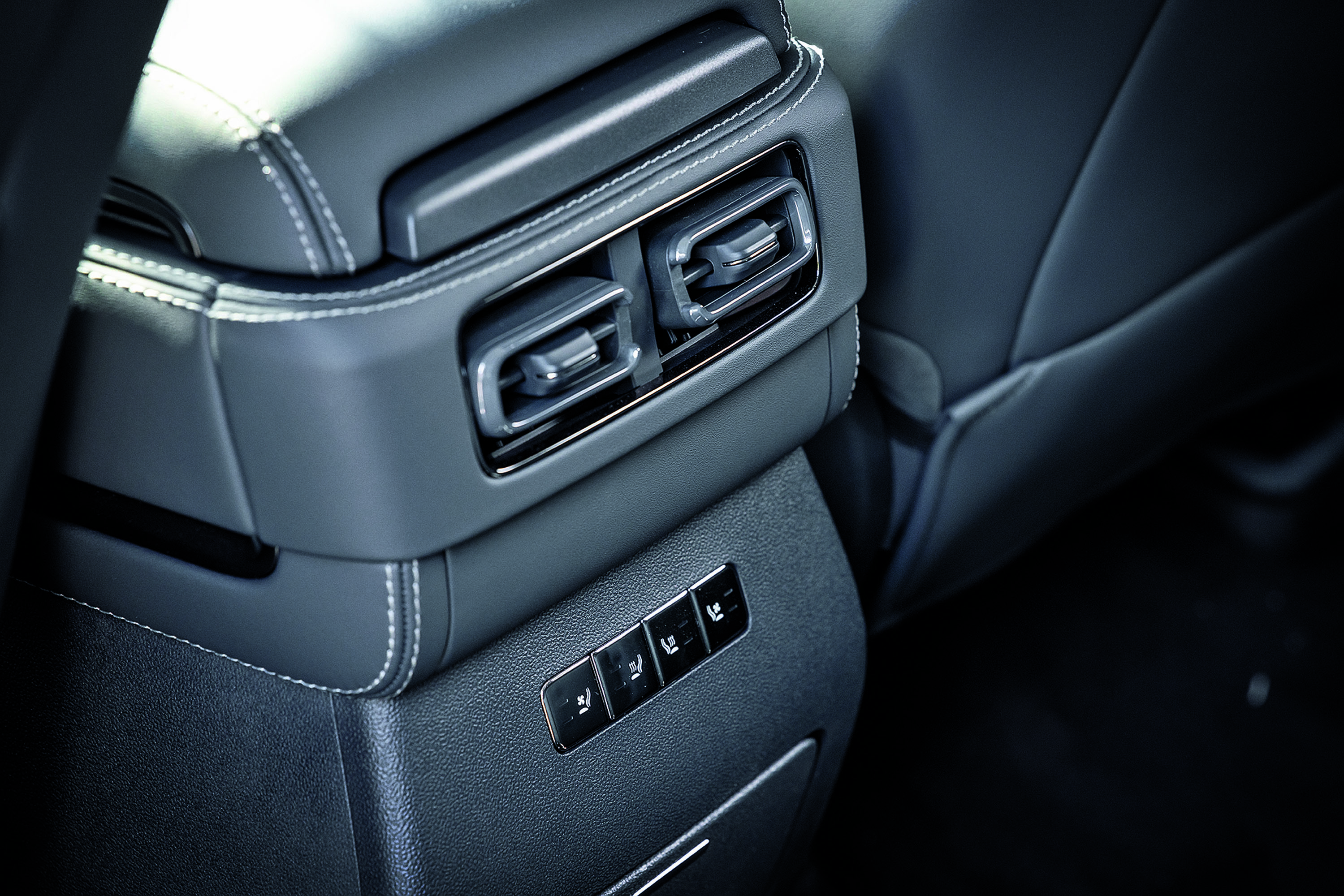 Interior de carro com sa&iacute;das de ar e bot&otilde;es de controle de assento no console traseiro, estofamento cinza escuro com costura branca